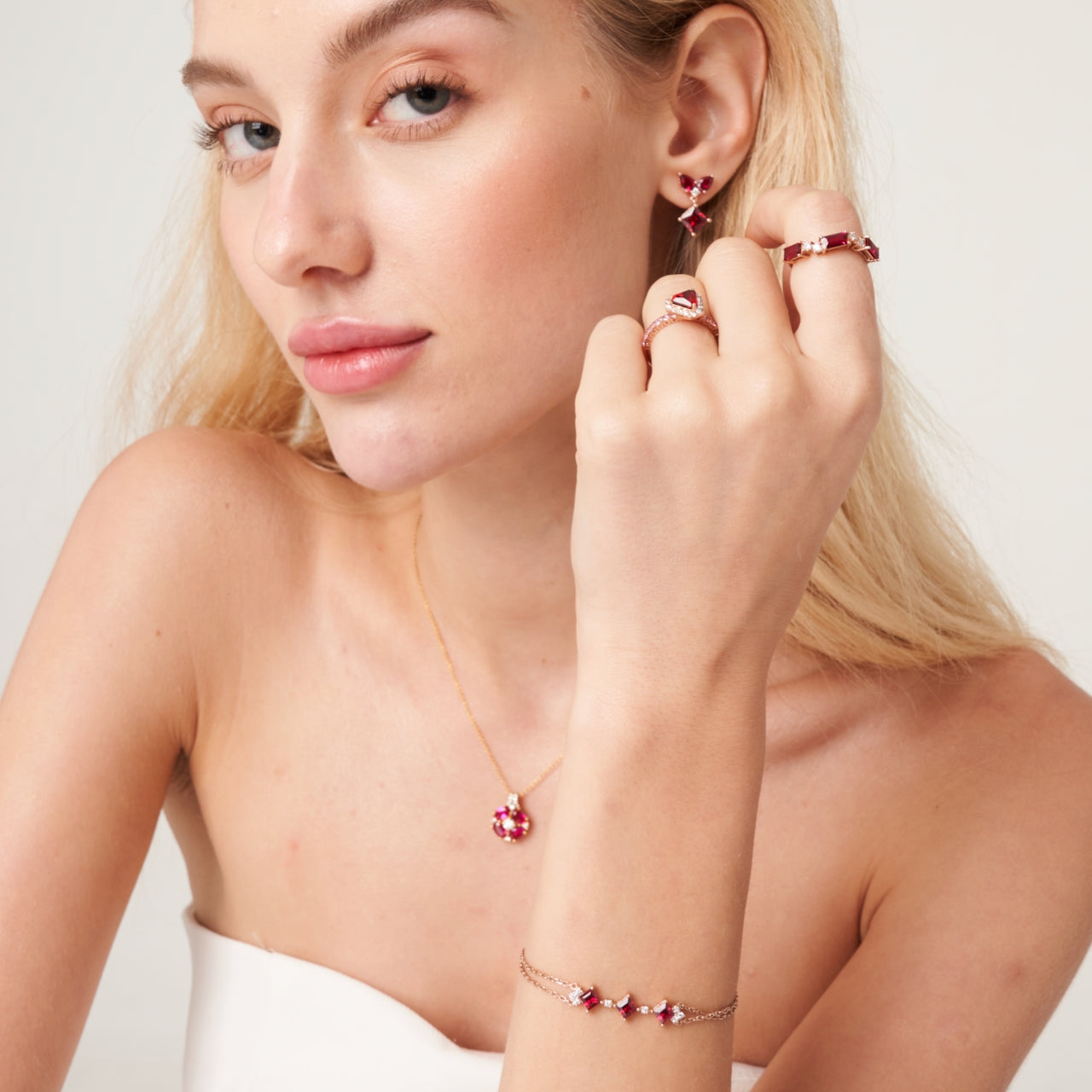 A model wearing Forma ring and bracelet set with lab grown diamond and ruby. She also wears Diana ring, Amore earrings and Pristi necklace all set with lab grown ruby and diamonds.