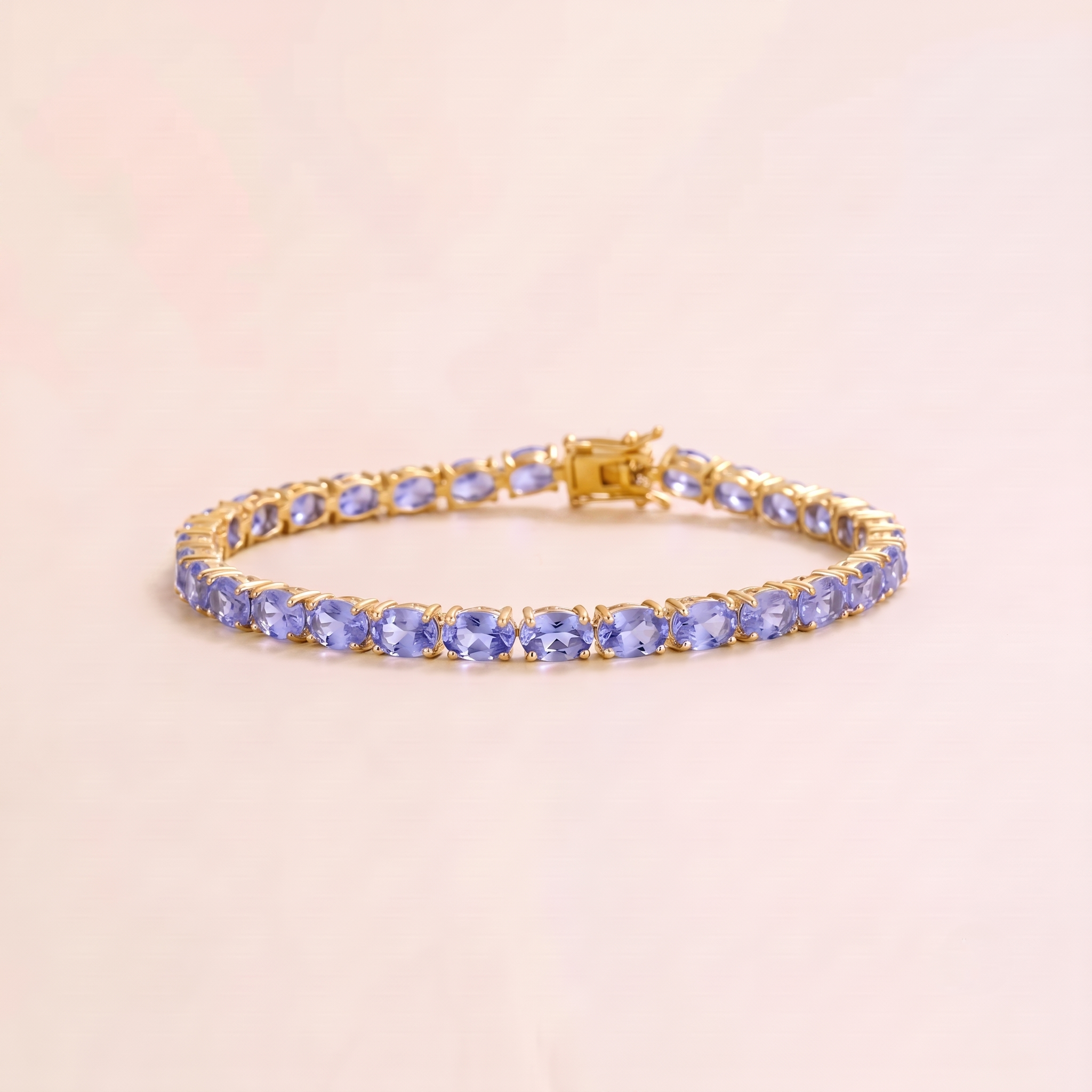 A gold tennis bracelet set with oval light blue sapphire gemstones.