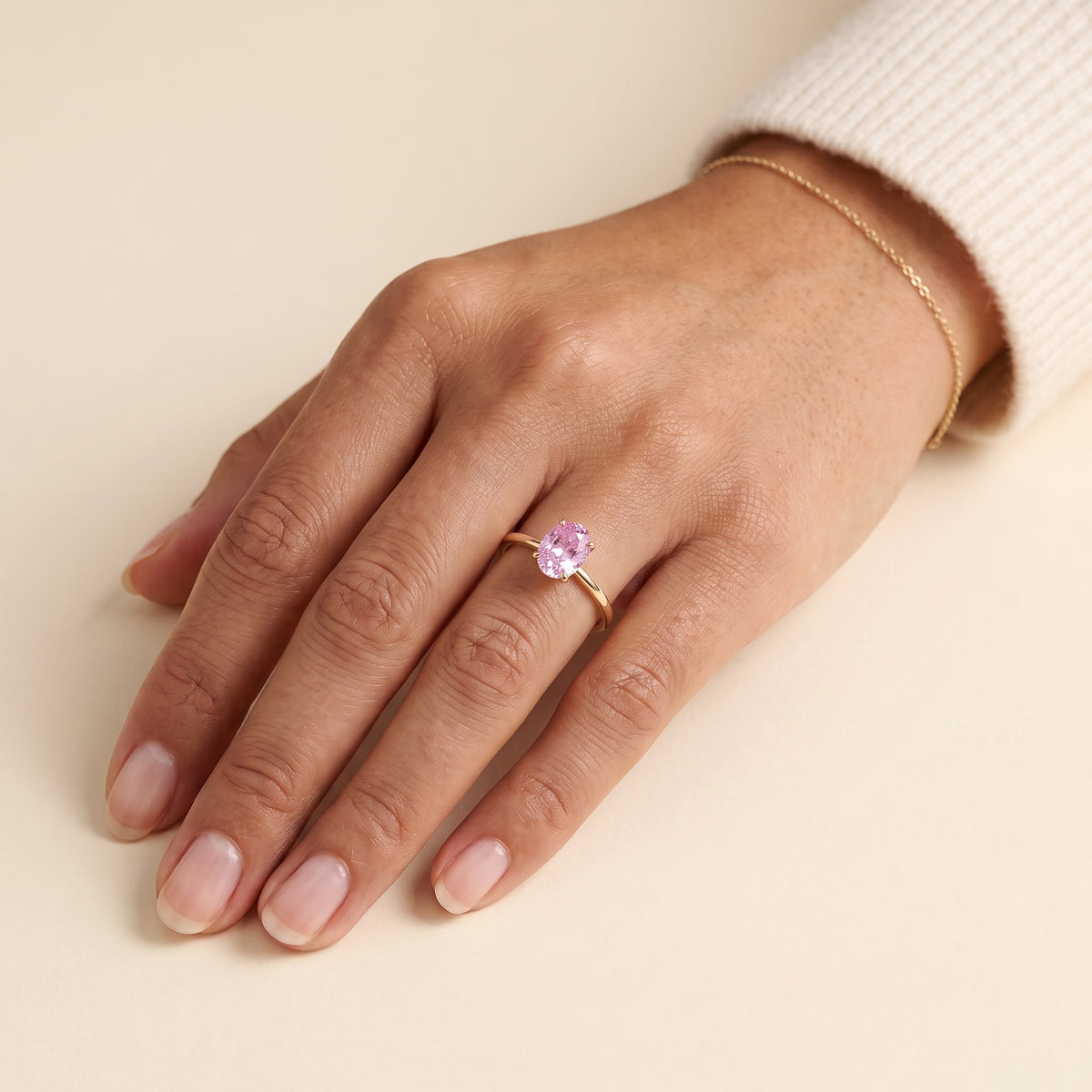 A model is wearing Lyra Oval Shape Pastel Pink Sapphire Cathedral Solitaire Ring in Gold