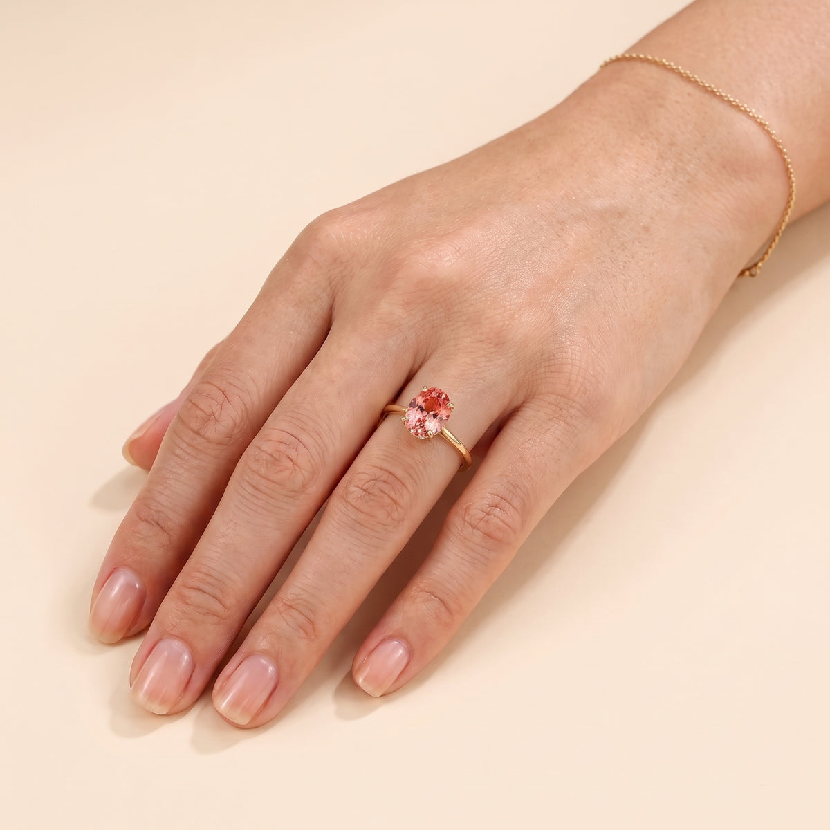 A model is wearing Lyra Oval Shape Padparadscha Sapphire Cathedral Solitaire Ring in Gold