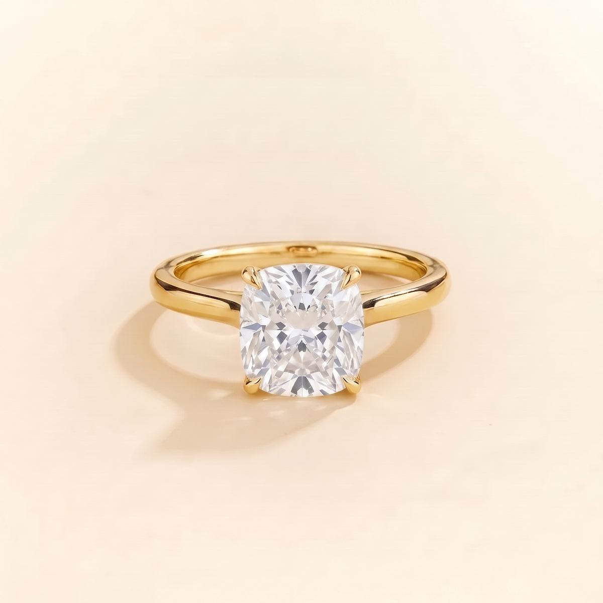 Solitaire engagement ring with a 2 carat cushion-cut diamond in a four-prong cathedral setting on a slim polished 18K yellow gold band.