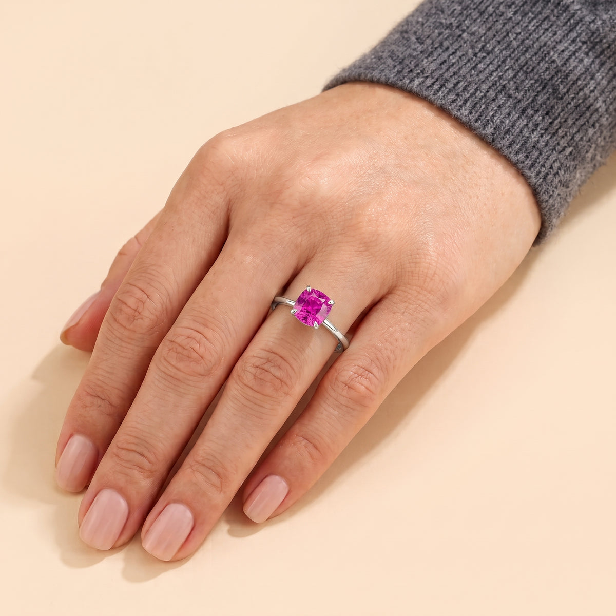 A model is wearing Iris Cushion Shape Vivid Pink Sapphire Cathedral Solitaire