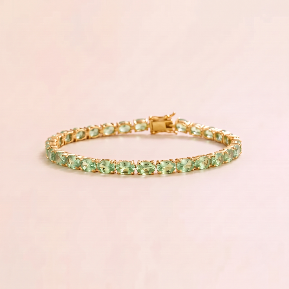 A gold tennis bracelet set with oval green sapphire gemstones.