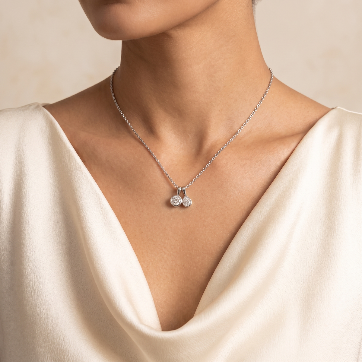 Angled view of the Prunus diamond necklace in white gold showing the round and pear diamond, Juvetti London