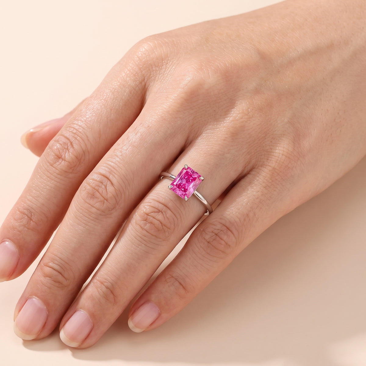 A Model is wearing The Clair Radiant Shape Vivid Pink Sapphire Cathedral Solitaire Ring