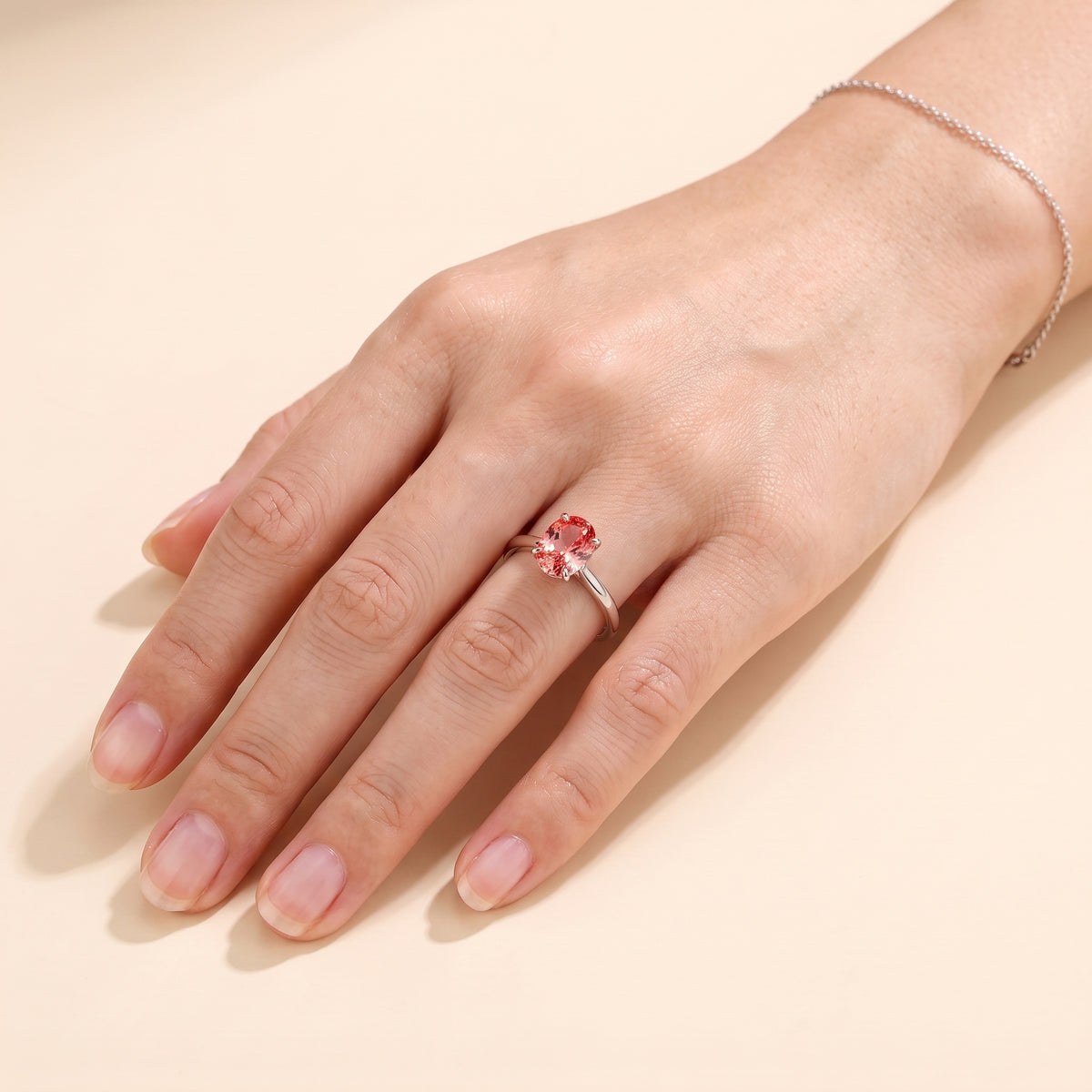 A model is wearing Lyra Oval Shape Padparadscha Sapphire Cathedral Solitaire Ring in White Gold