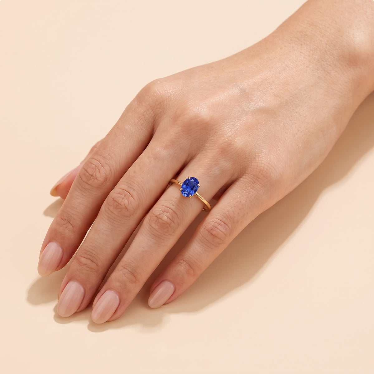 The model is wearing Lyra Oval Shape Blue Sapphire Cathedral Solitaire Ring in Gold