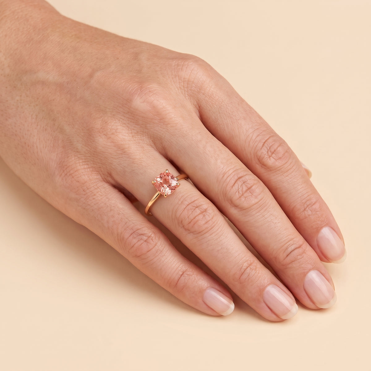 A model is wearing Iris Cushion Shape Padparadscha Sapphire Cathedral Solitaire