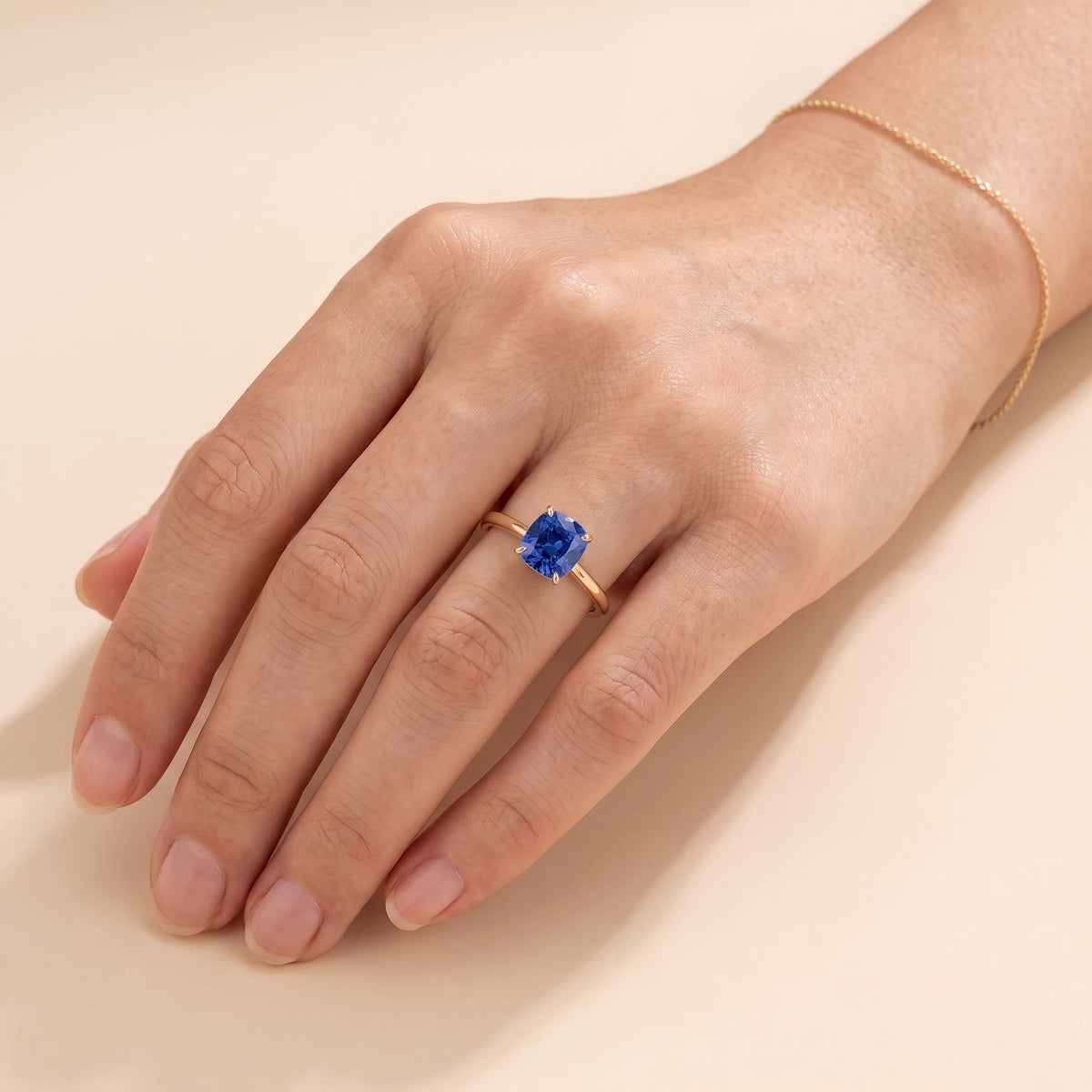 A model is wearing Iris Cushion Shape Blue Sapphire Cathedral Solitaire