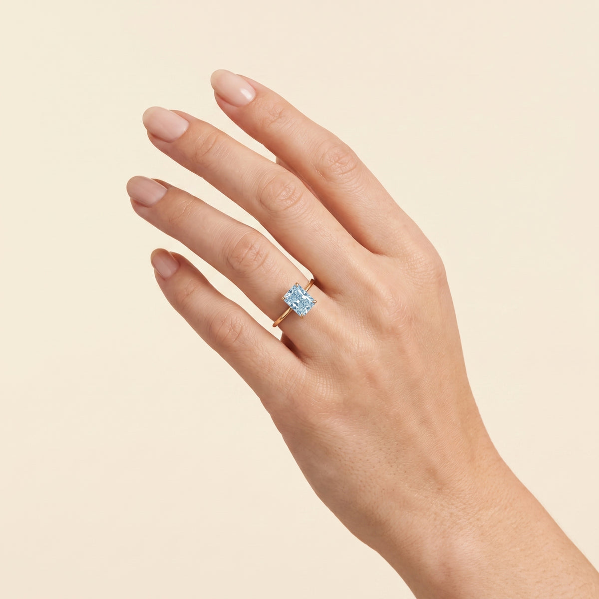 A model is wearing Clair Radiant Shape Aquamarine Cathedral Solitaire Ring
