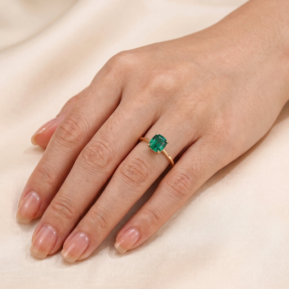 A model is wearing Iris Cushion Shape Emerald Cathedral Solitaire