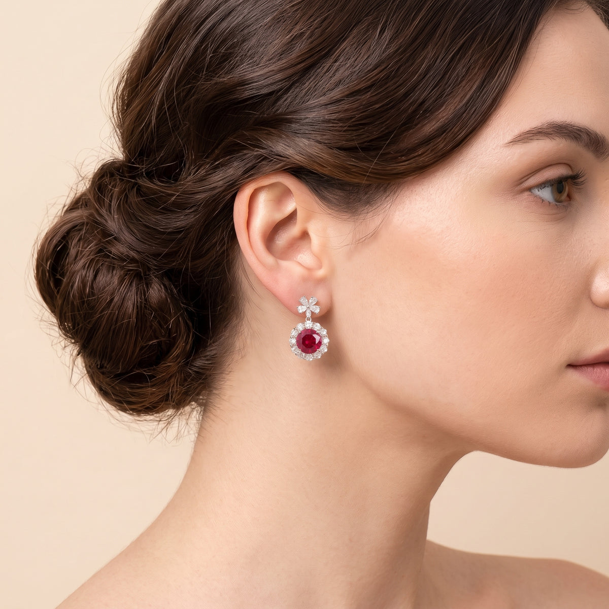 A model is wearing The Antoinette Round Ruby & Diamond Halo Pendant Earrings with Flower Bail
