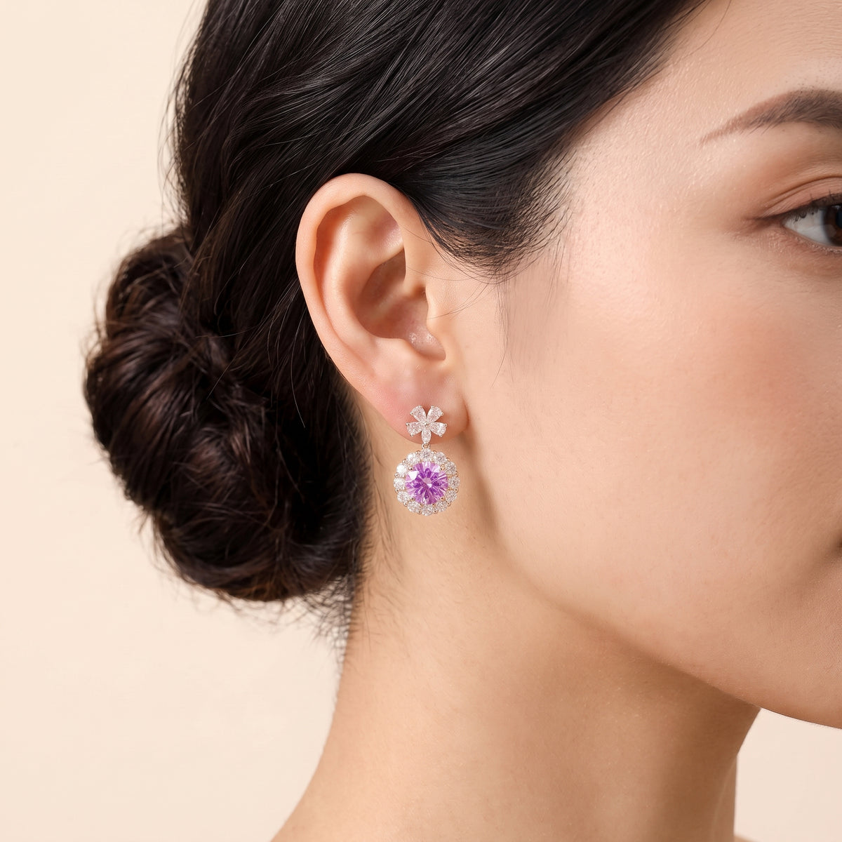 A model is wearing The Antoinette Round Purple Sapphire & Diamond Halo Pendant Earrings with Flower Bail