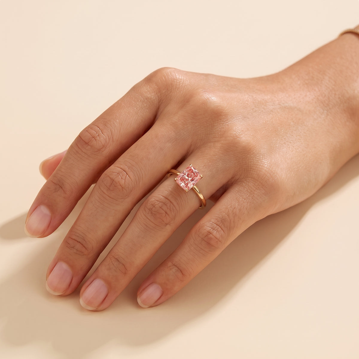 A model is wearing Clair Radiant Shape Padparadscha Sapphire Cathedral Solitaire Ring