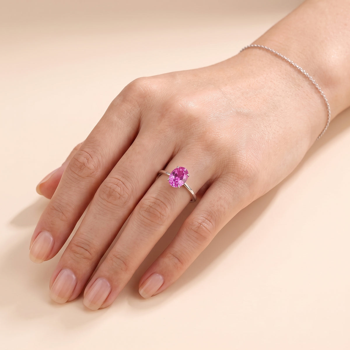 A model is wearing Lyra Oval Shape Vivid Pink Sapphire Cathedral Solitaire Ring in White Gold