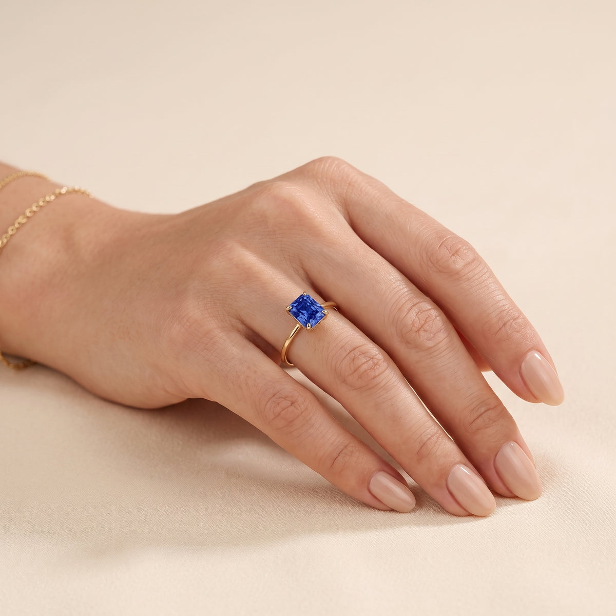 A model is wearing Clair Radiant Shape Blue Sapphire Cathedral Solitaire Ring