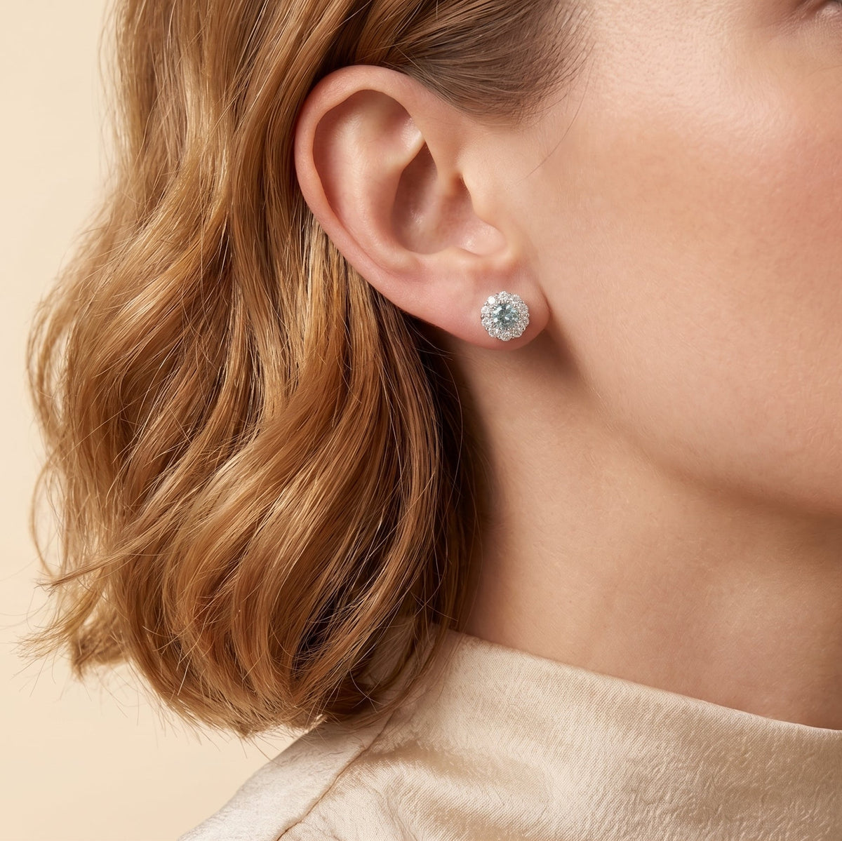 A model is wearing Talia Round Aquamarine & Diamond Halo Stud Earrings