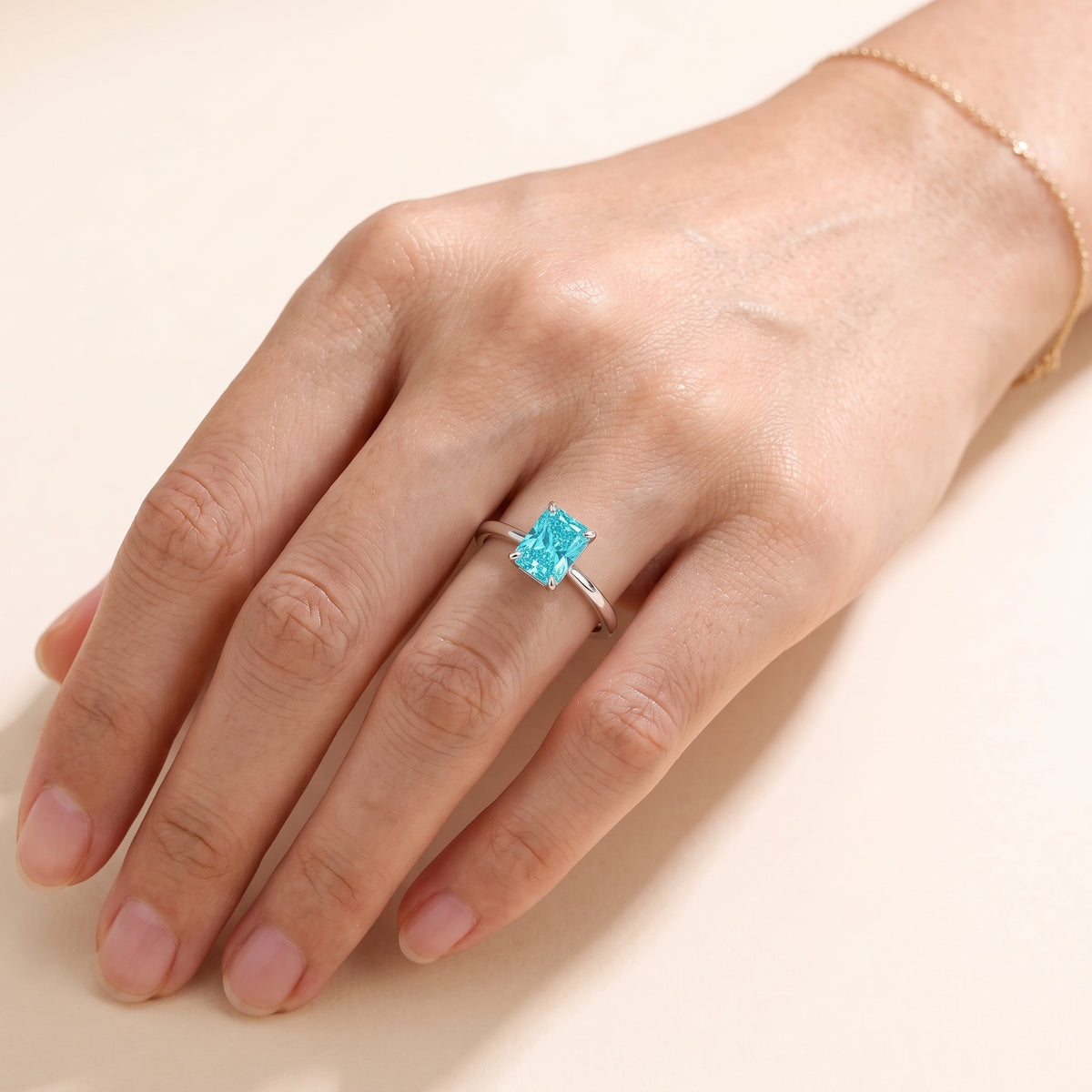A model is wearing The Clair Radiant Shape Paraiba Cathedral Solitaire Ring
