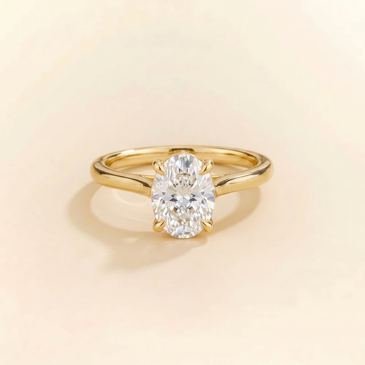 Solitaire engagement ring with a 2 carat oval-cut diamond in a four-prong cathedral setting on a slim polished 18K yellow gold band.