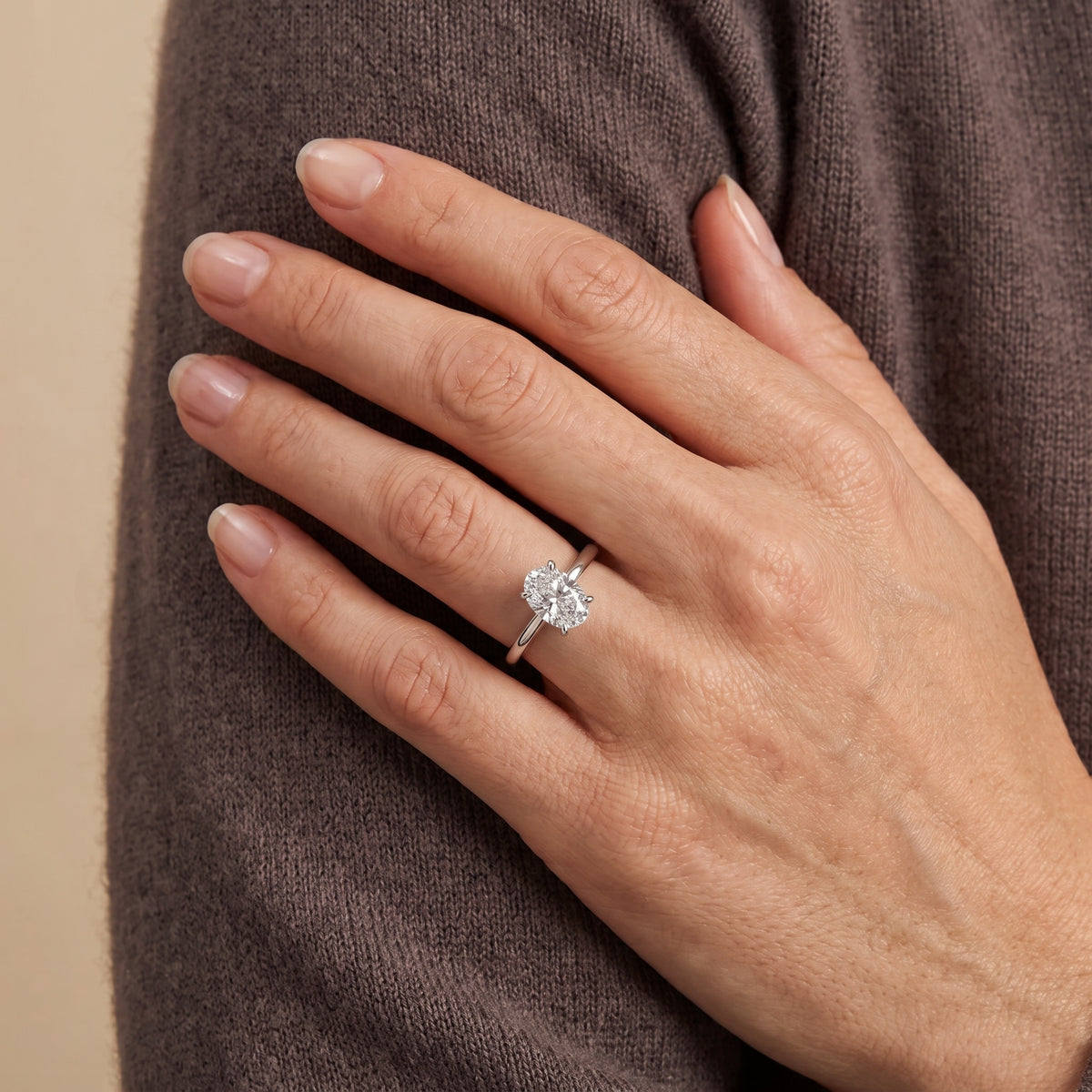The model is wearing Lyra Oval Shape Diamond Cathedral Solitaire Ring in White Gold
