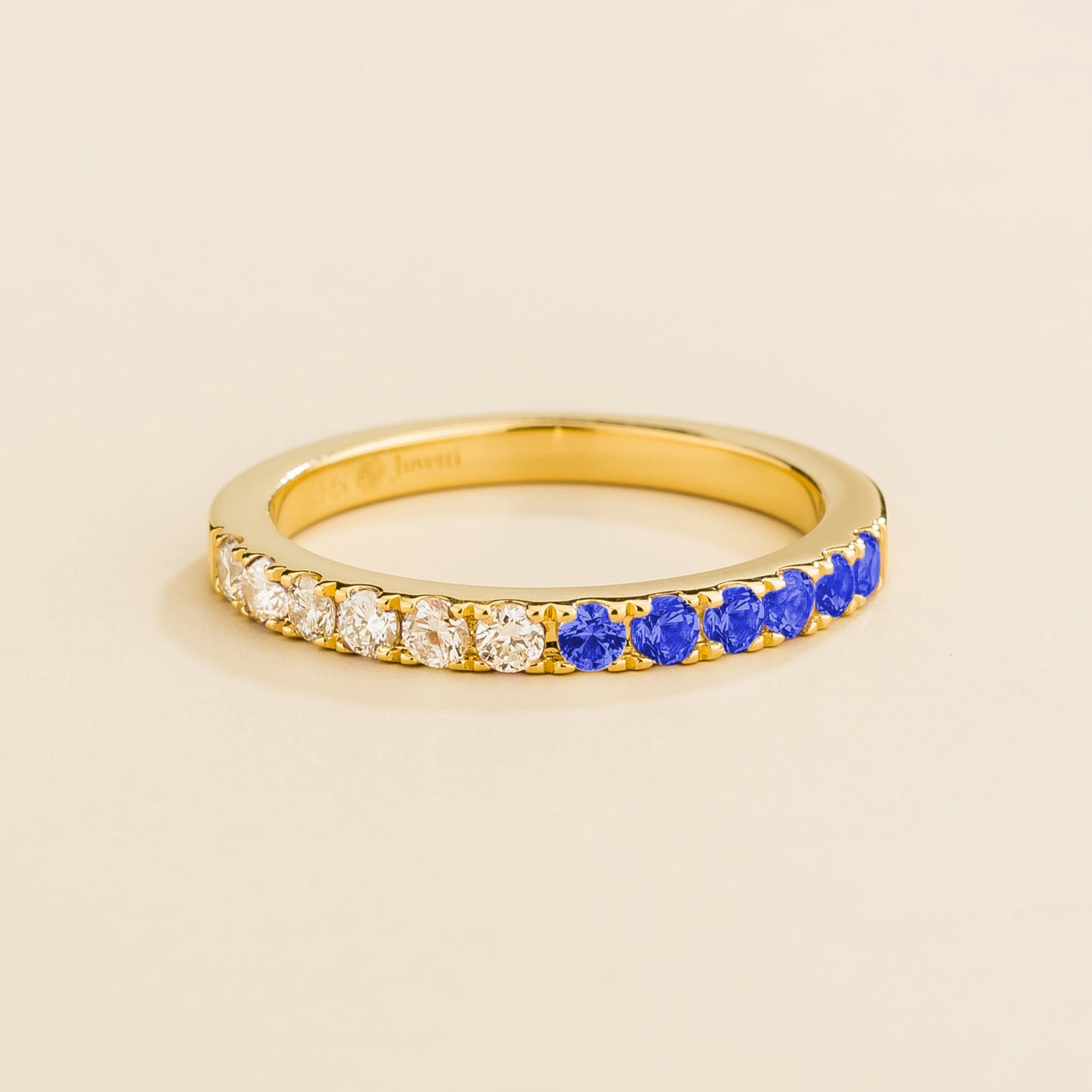 Juvetti yellow gold band featuring round lab-grown diamonds and blue sapphires set in a half-eternity design.