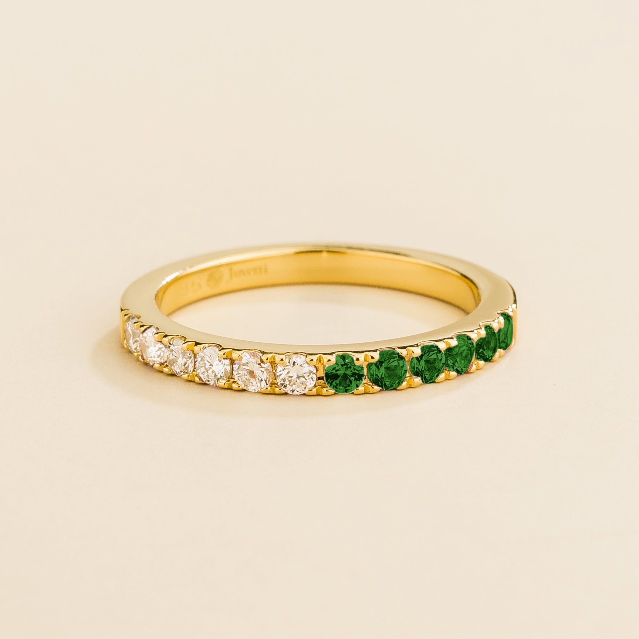 Juvetti yellow gold band featuring round lab-grown diamonds and emeralds set in a half-eternity design.