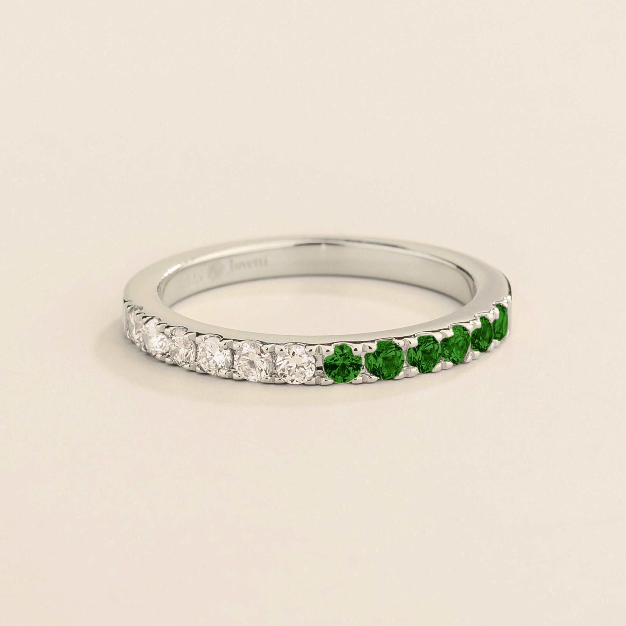 Juvetti white gold band featuring round lab-grown diamonds and emeralds set in a half-eternity design.