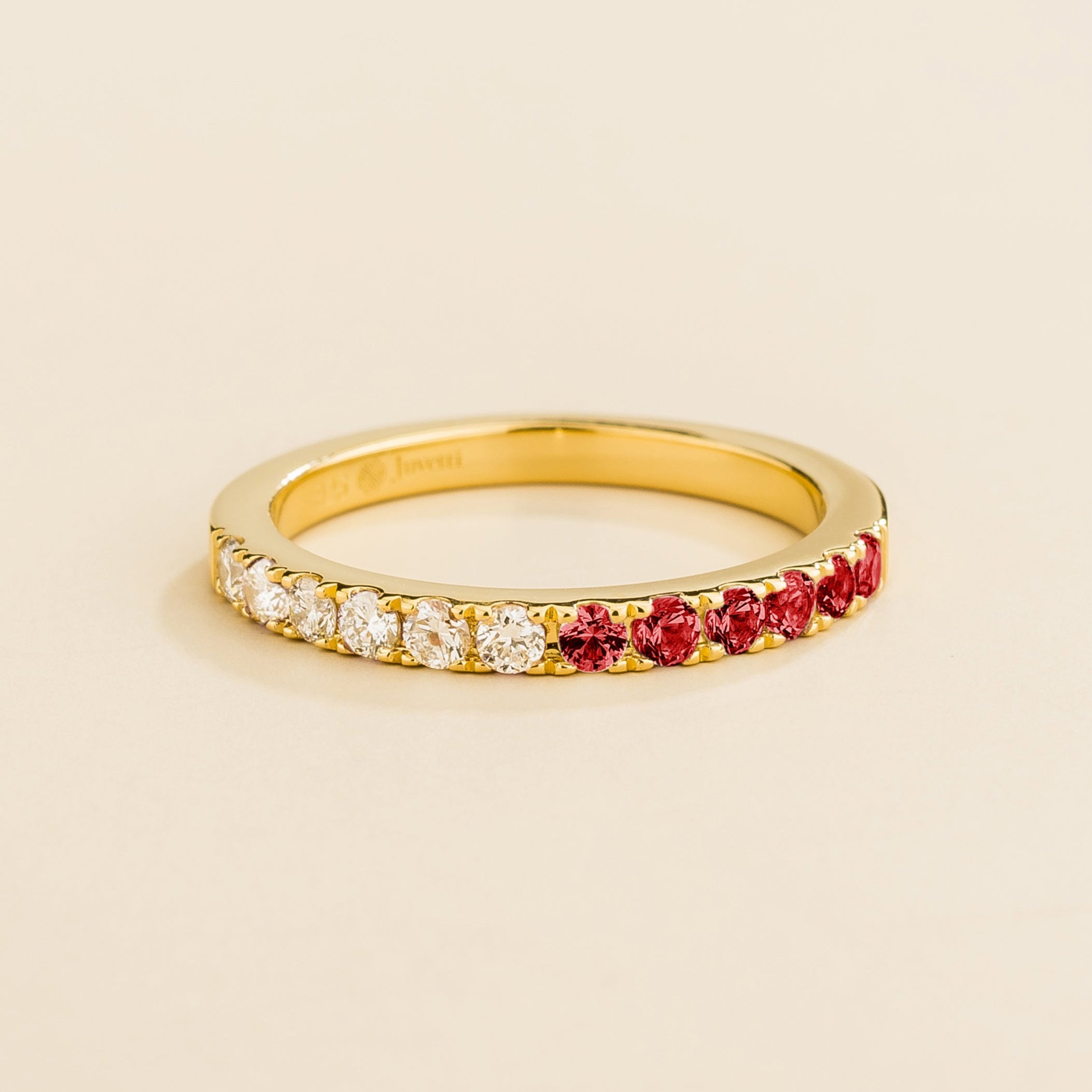 Juvetti yellow gold band featuring round lab-grown diamonds and ruby set in a half-eternity design.