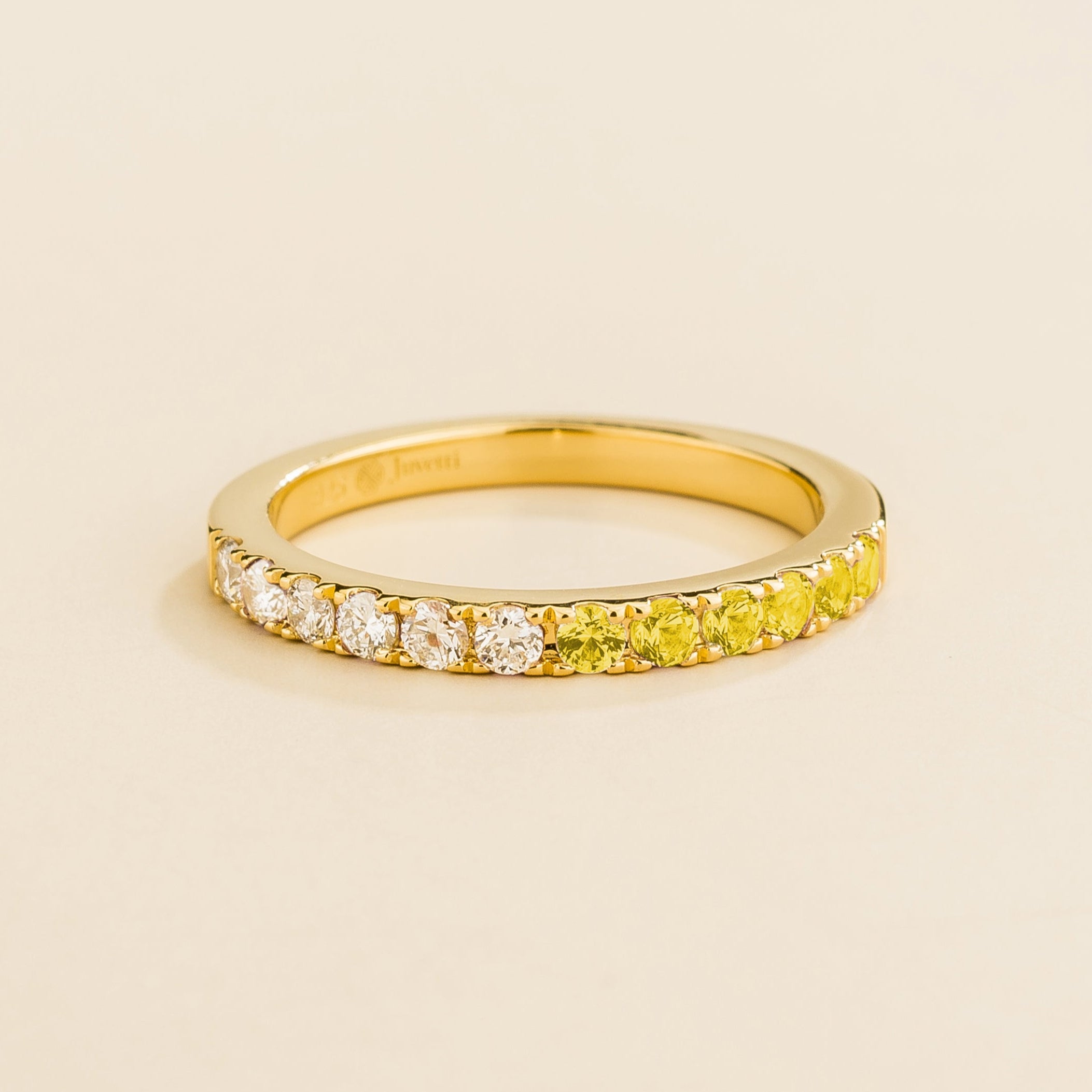 Juvetti yellow gold band featuring round lab-grown diamonds and yellow sapphire set in a half-eternity design.