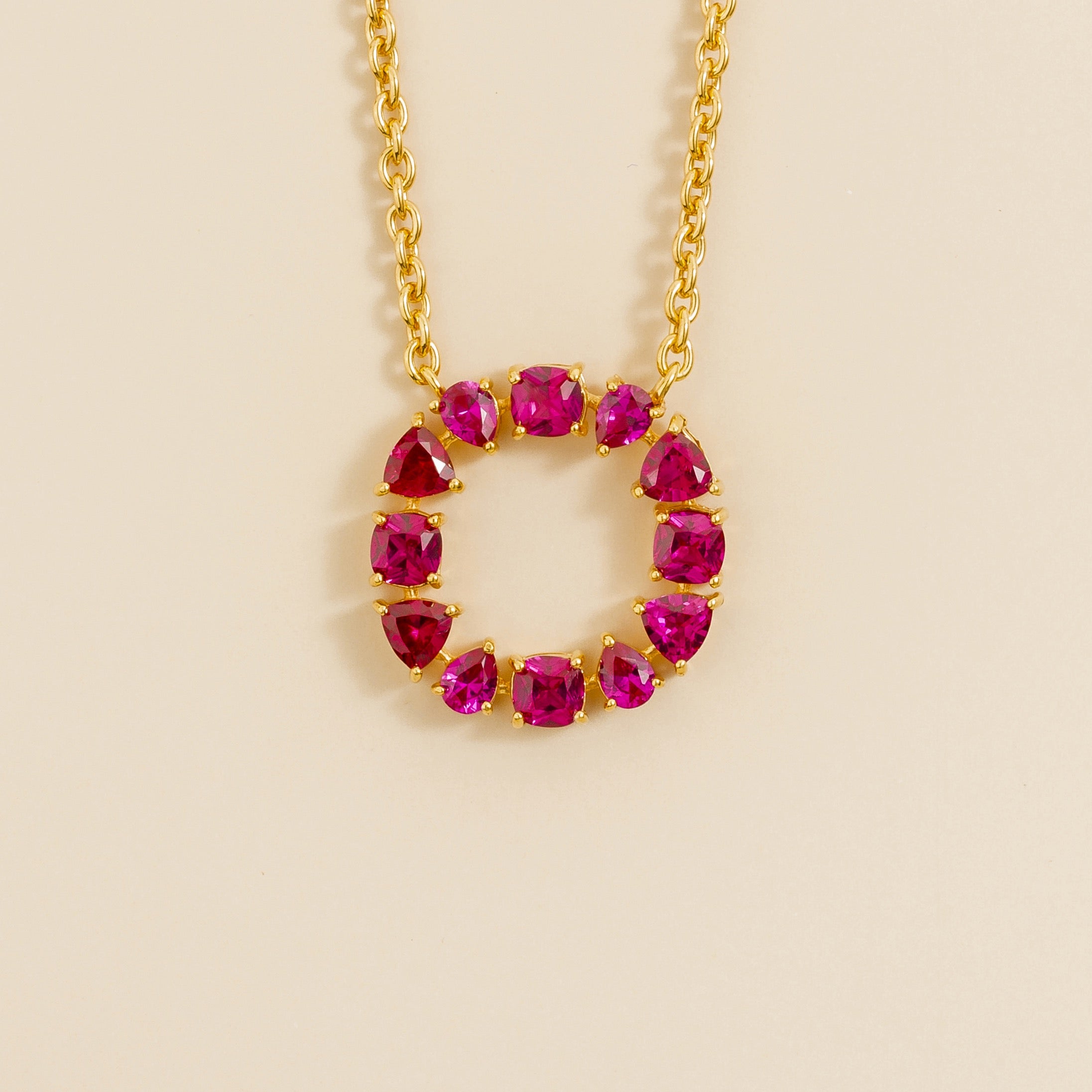 A gold necklace with a circular pendant featuring multiple red ruby gemstones arranged in a circle.