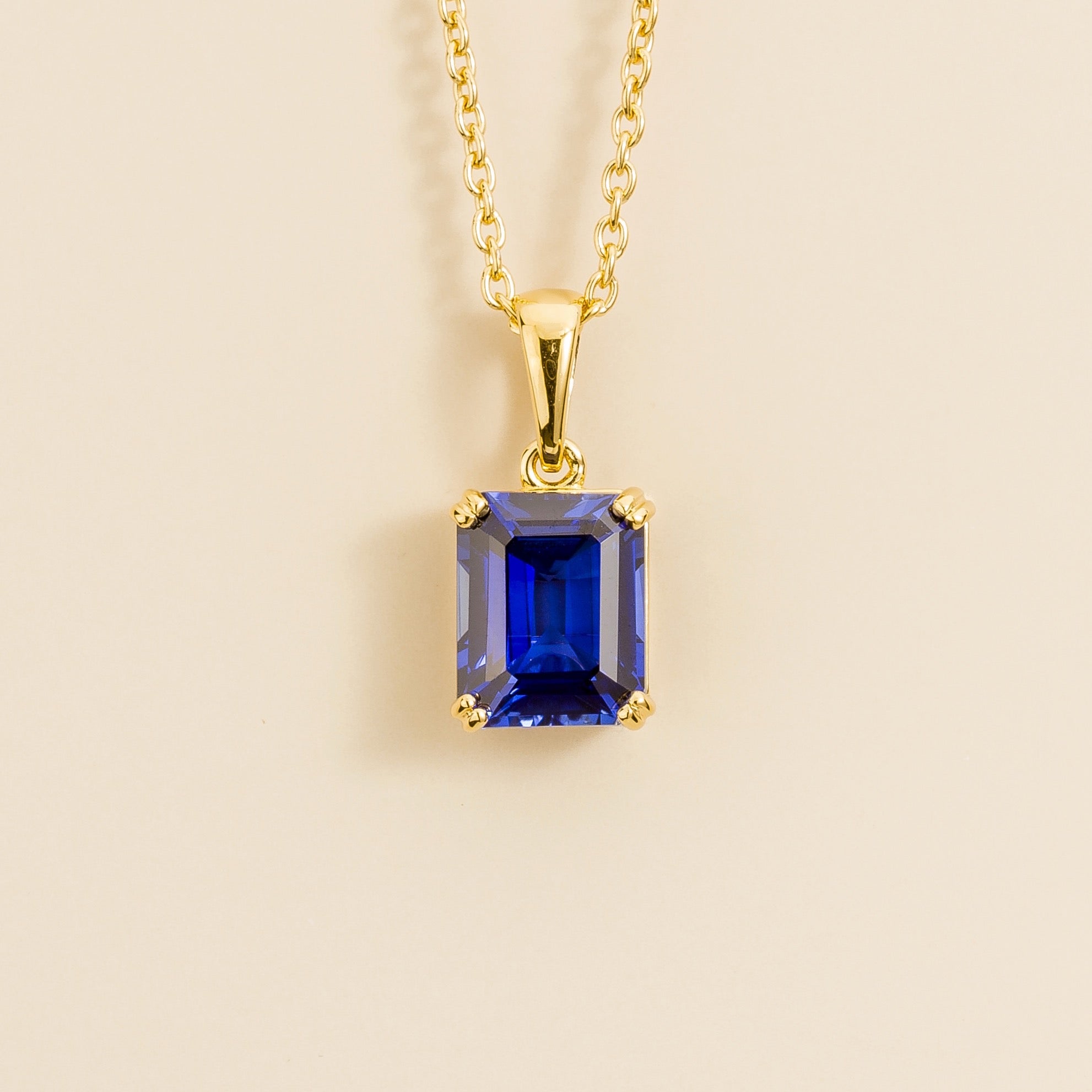A gold pendant necklace with an emerald-cut blue sapphire centerpiece, London jewellery store