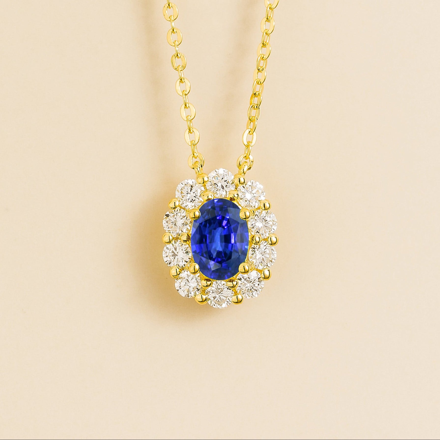Gold necklace with an oval blue sapphire and diamond halo accents. London jewellery store