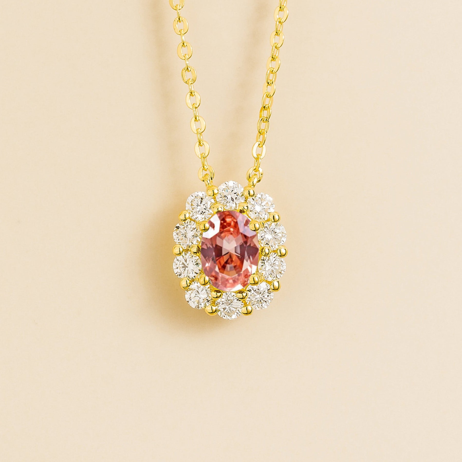 Prill Necklace in Gold set with oval Padparadscha Sapphire and round halo Diamonds.