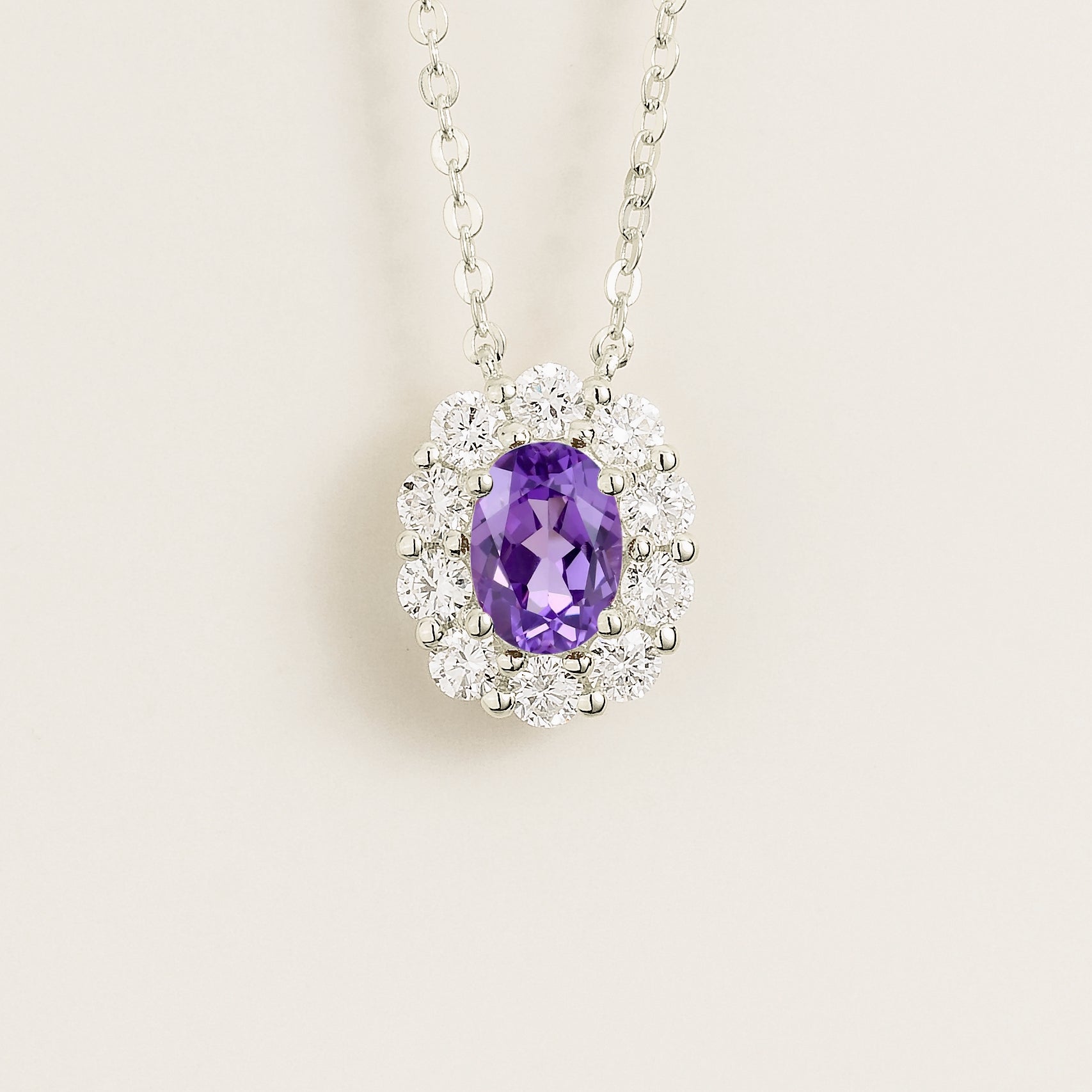 Oval purple sapphire gemstone necklace with round diamond halo on white gold chain. Juvetti London Jewellery