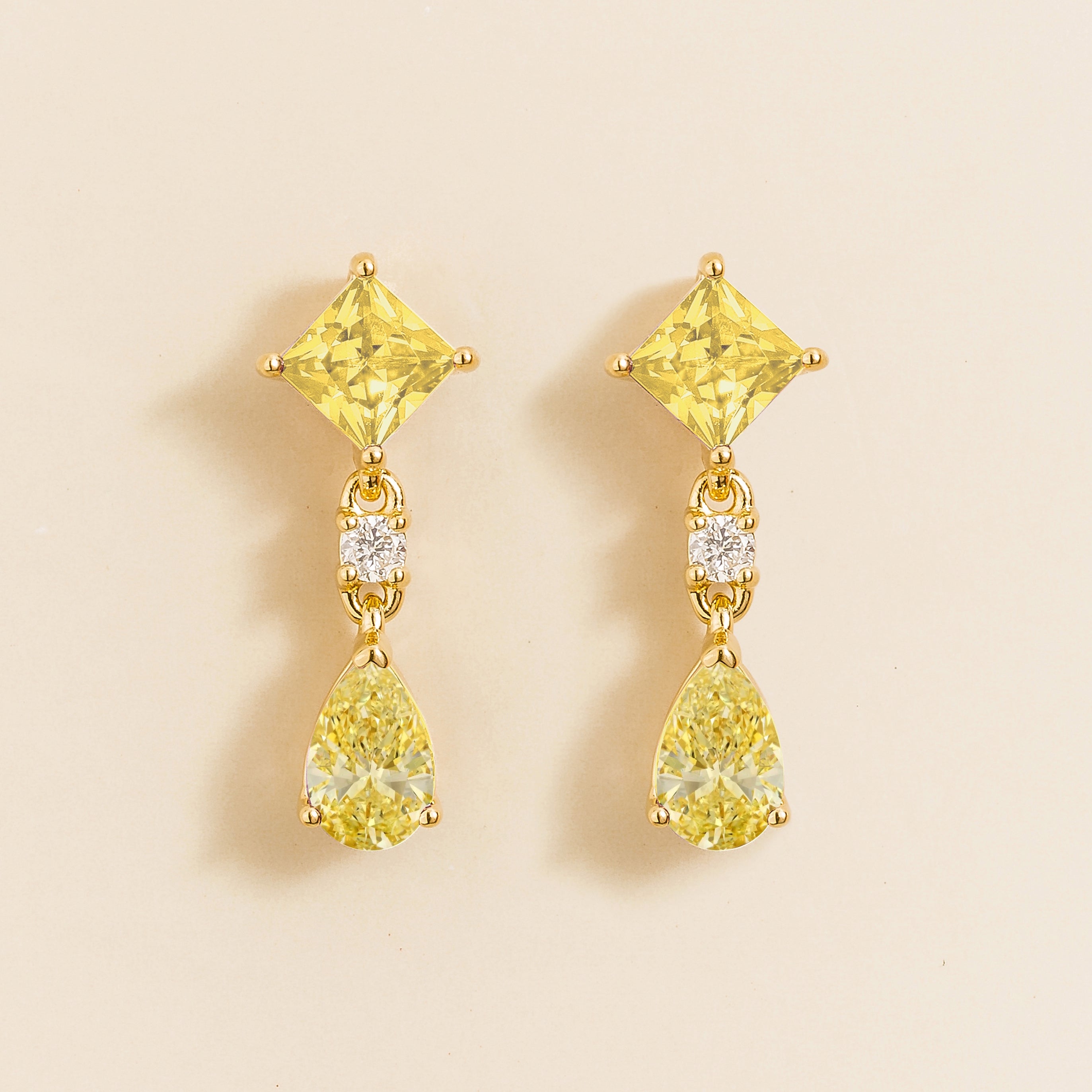 Ori drop earrings in gold set with princess cut square and pear Yellow sapphire and round Diamond.
