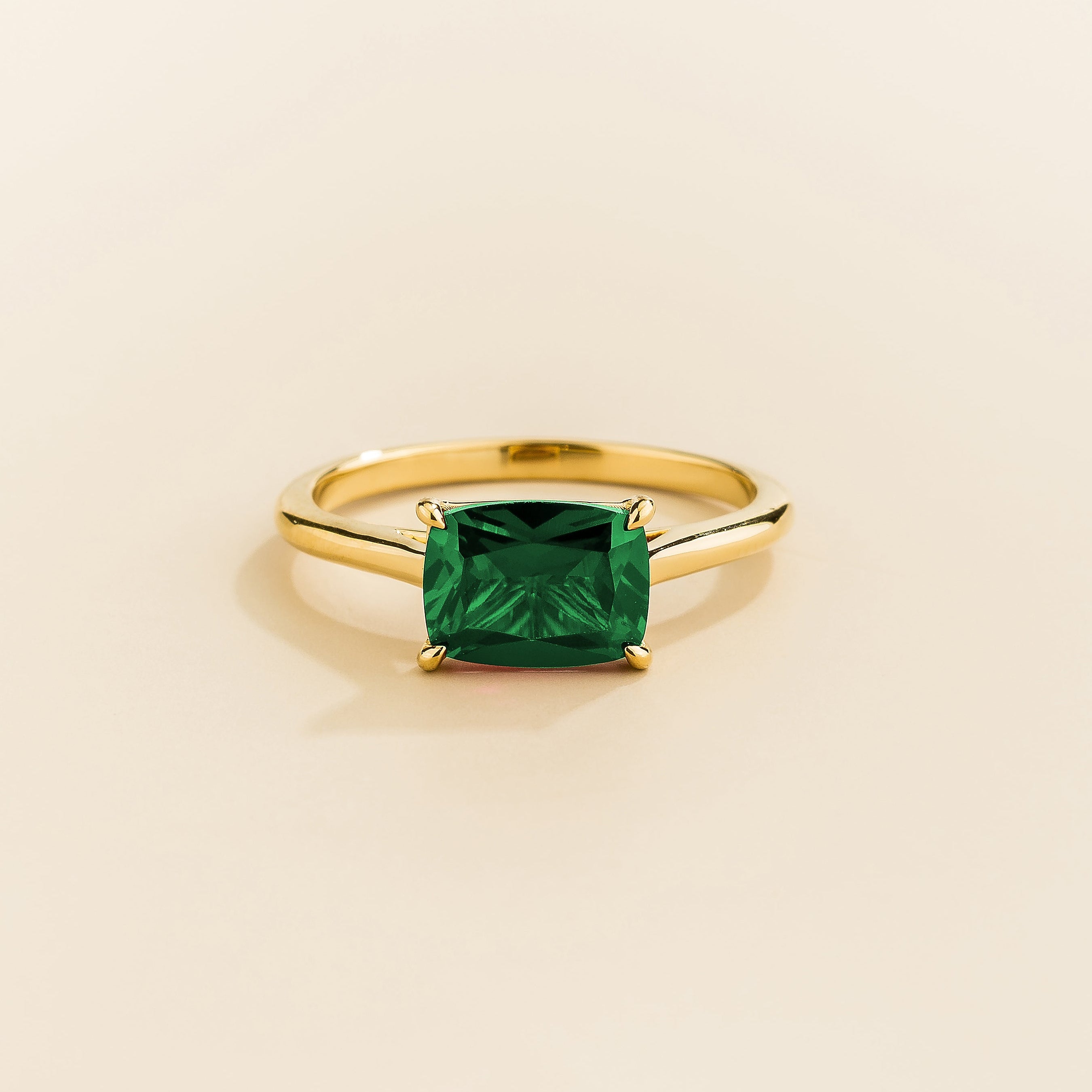 Juvetti yellow gold ring featuring a cushion-cut lab-grown emerald in an east–west setting.