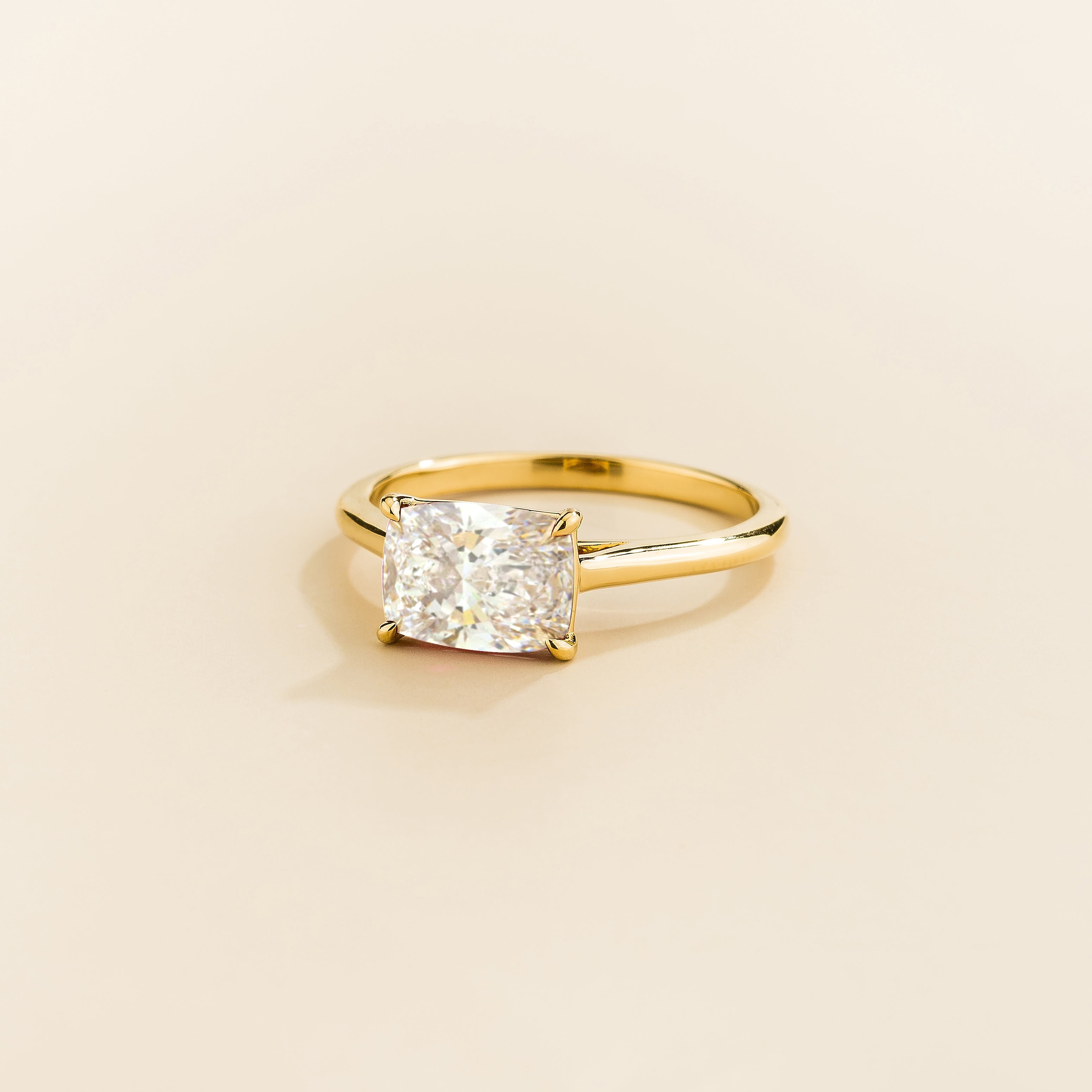 Juvetti yellow gold ring featuring a cushion-cut lab-grown diamond in an east–west setting.