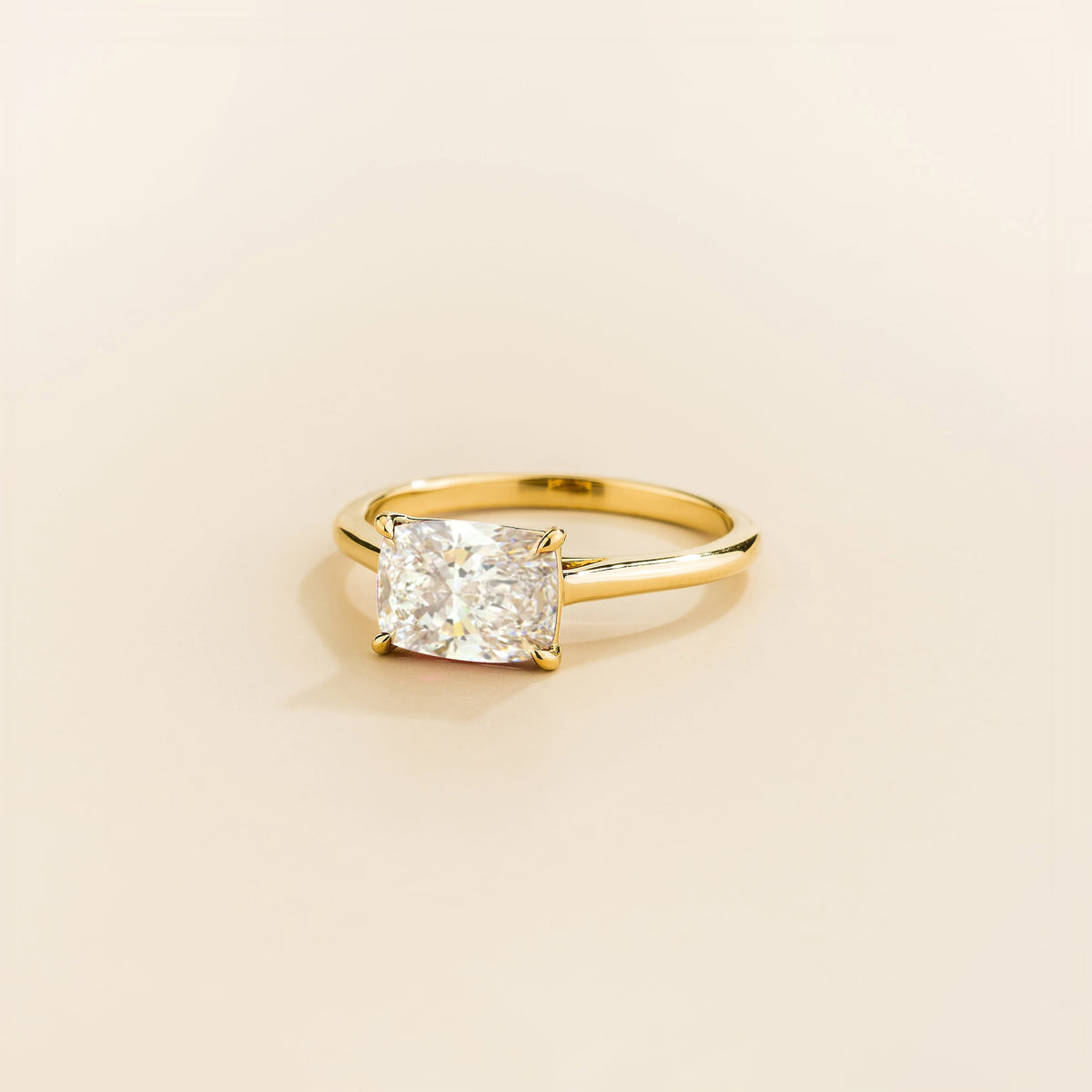 Juvetti yellow gold ring featuring a cushion-cut lab-grown diamond in an east–west setting.