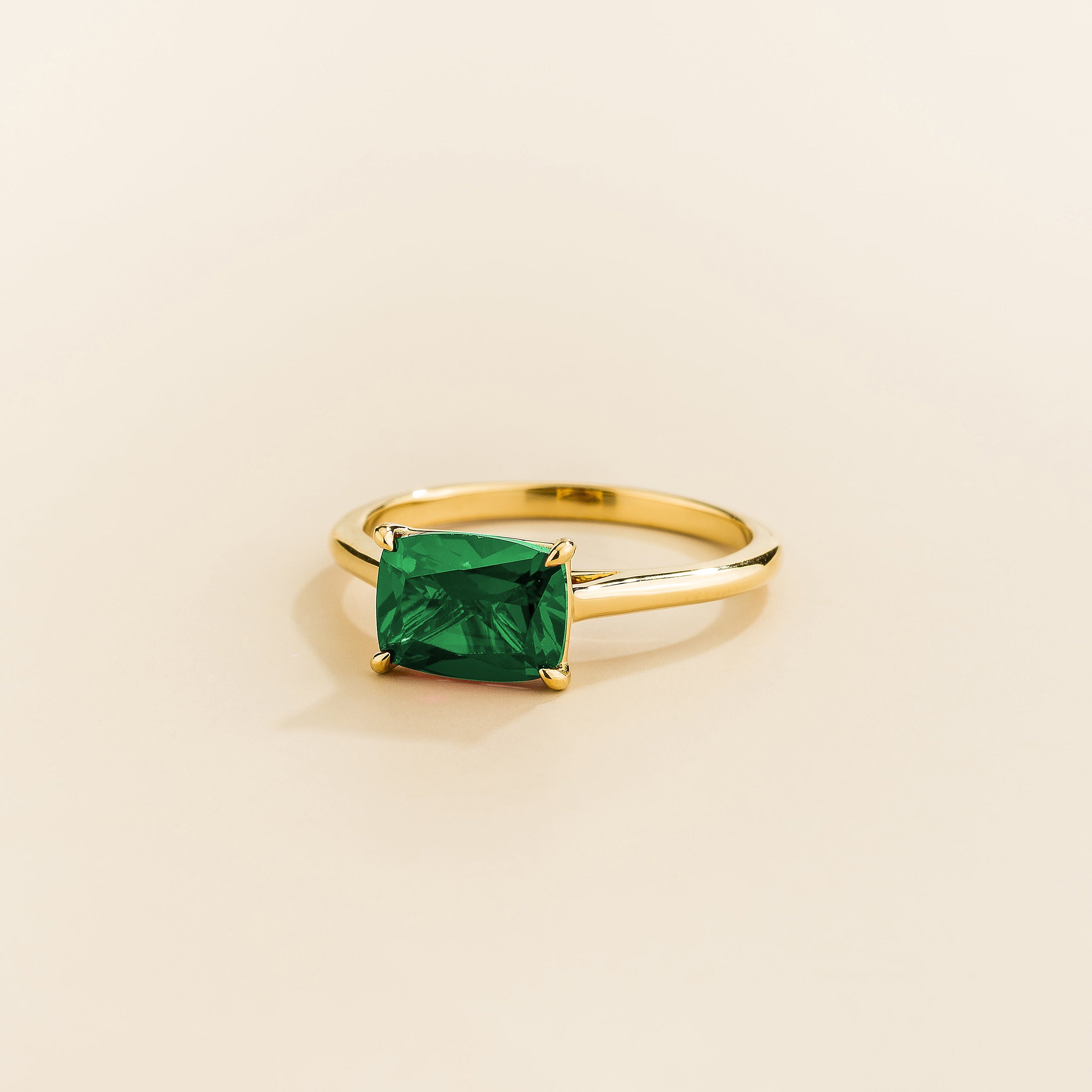 Juvetti yellow gold ring featuring a cushion-cut lab-grown emerald in an east–west setting.