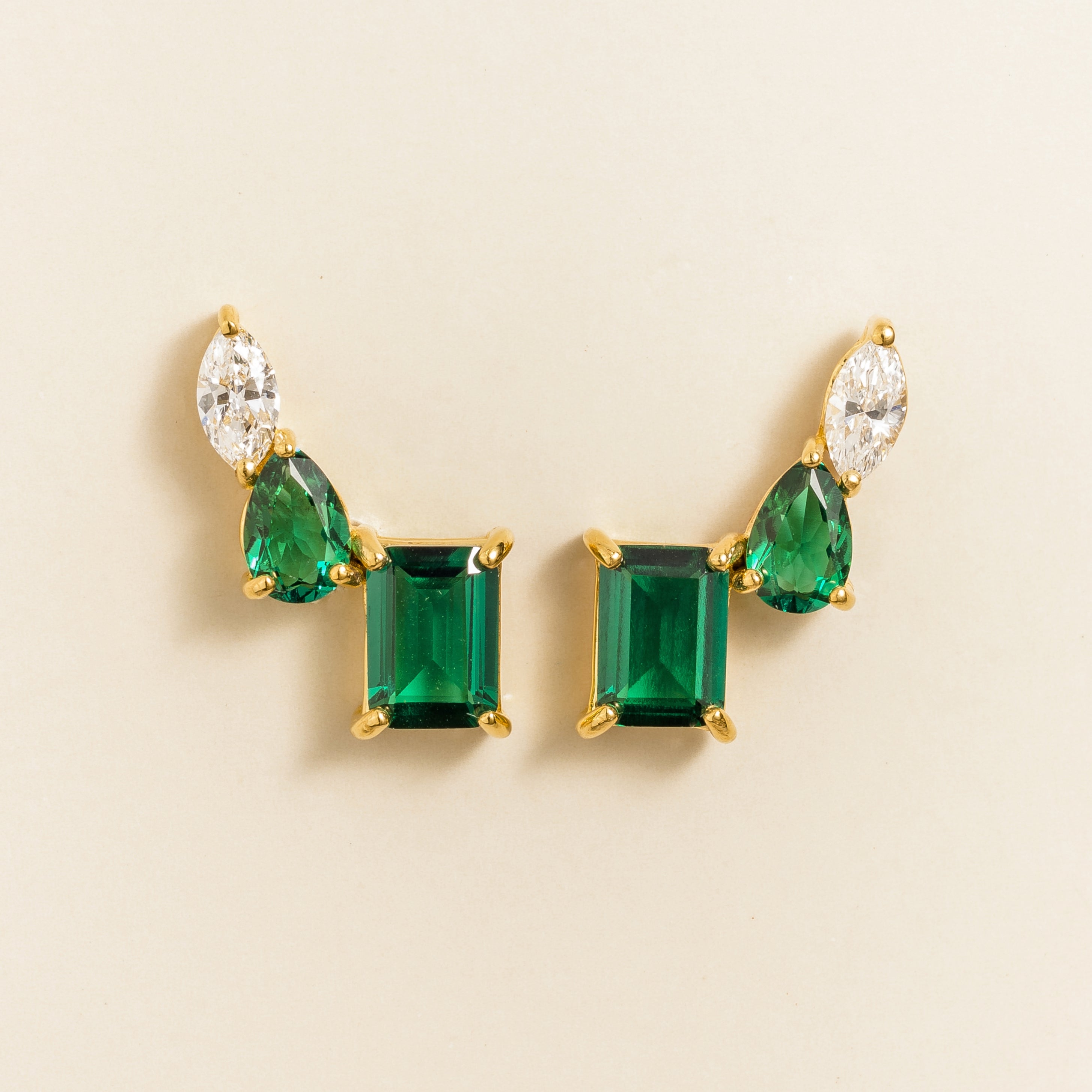 Juvetti yellow gold earrings featuring emerald-cut lab-grown emeralds with pear and marquise diamond accents.