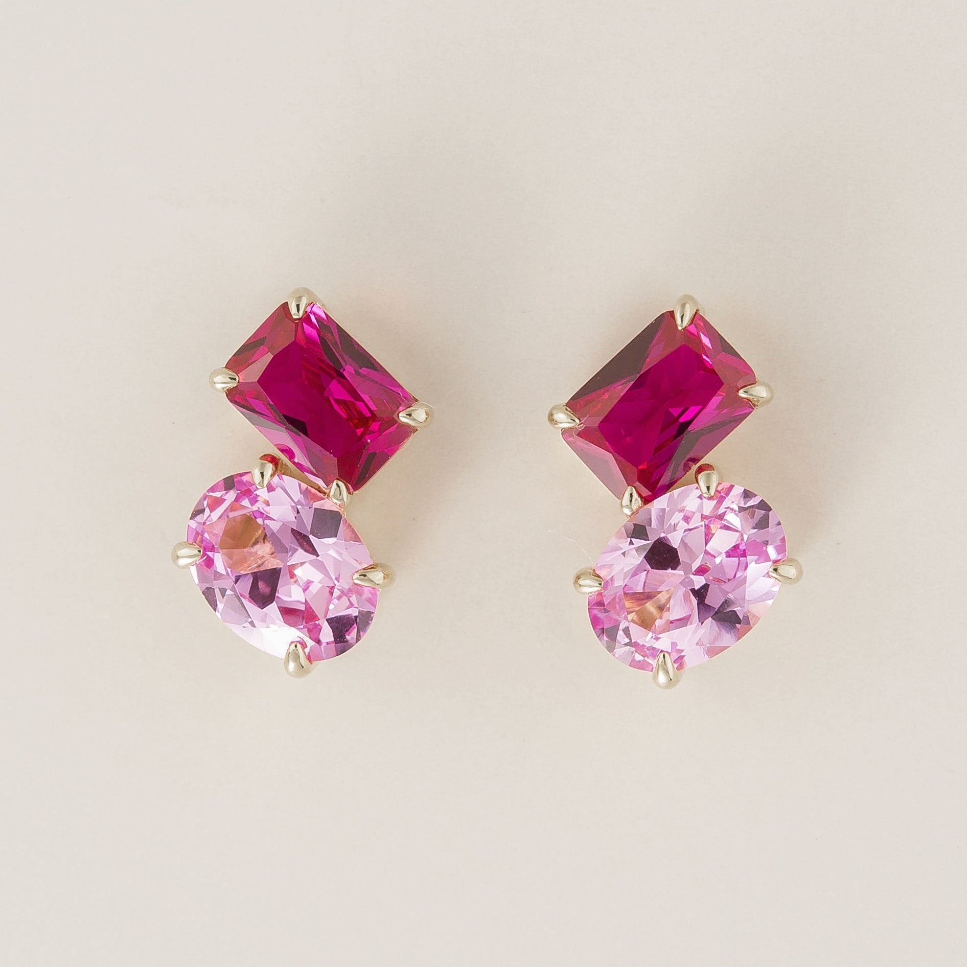 A pair of Toi et Moi white gold earrings featuring emerald vivid pink sapphire cut and oval cut pastel pink sapphires. London jewellery store