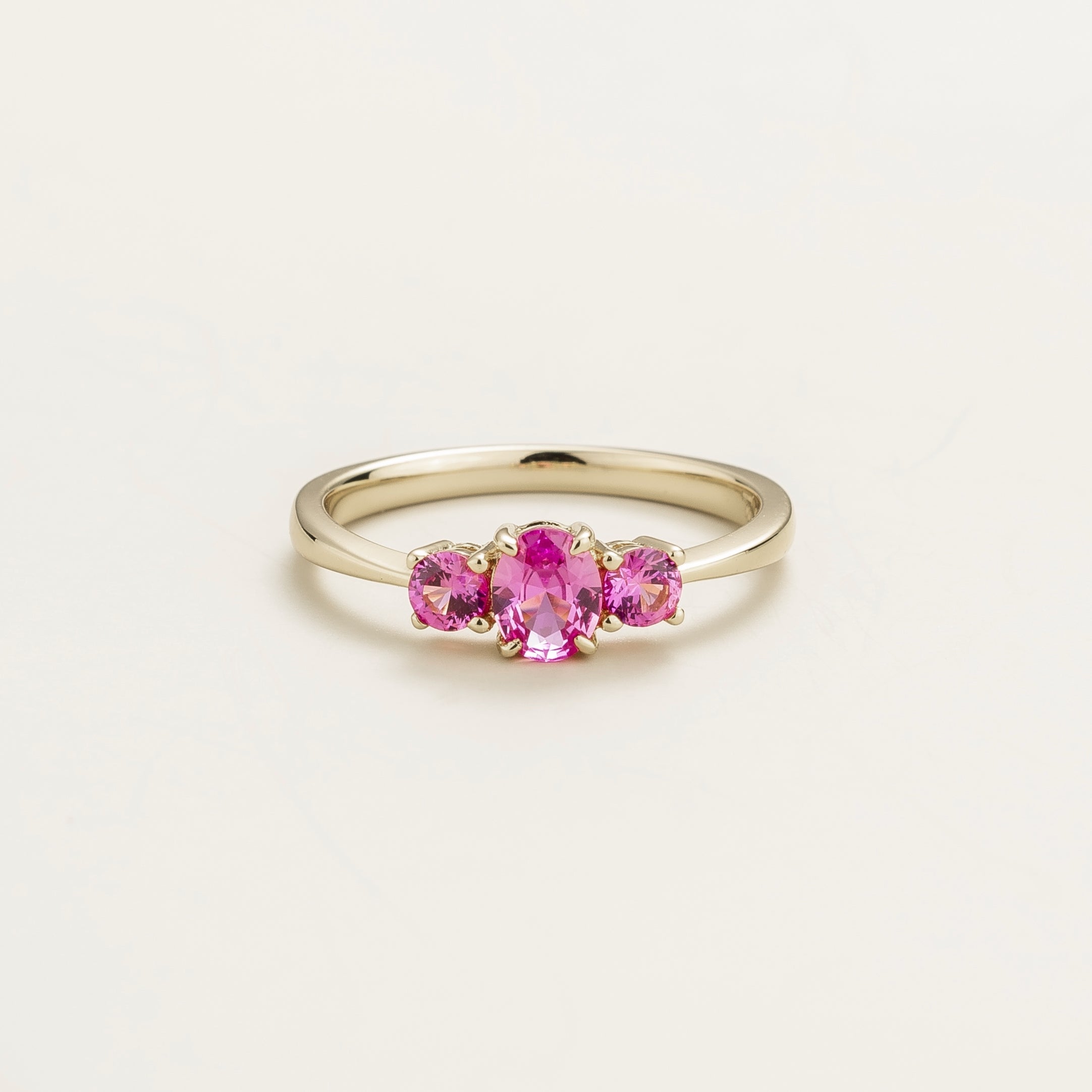 A white gold ring set with three pink sapphire gemstones, displayed against a plain background.