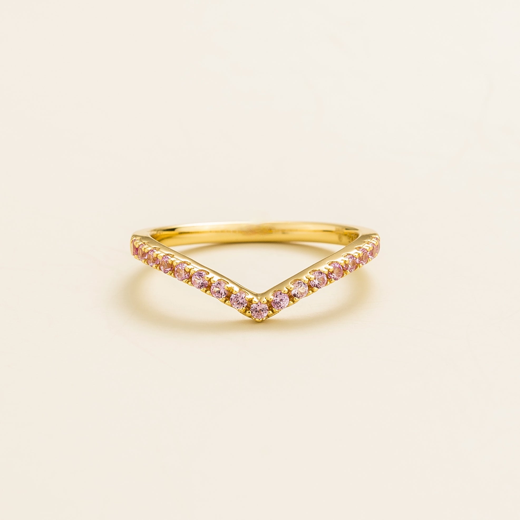 A yellow gold chevron ring with pink sapphires set in a V-shaped design.