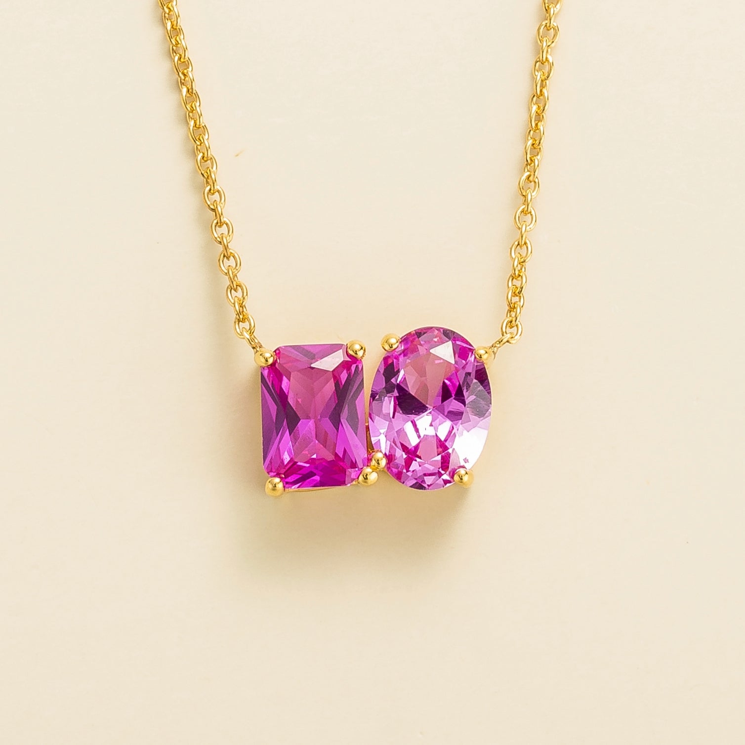Toi et Moi gold necklace featuring emerald vivid pink sapphire cut and oval cut pastel pink sapphires. London jewellery store