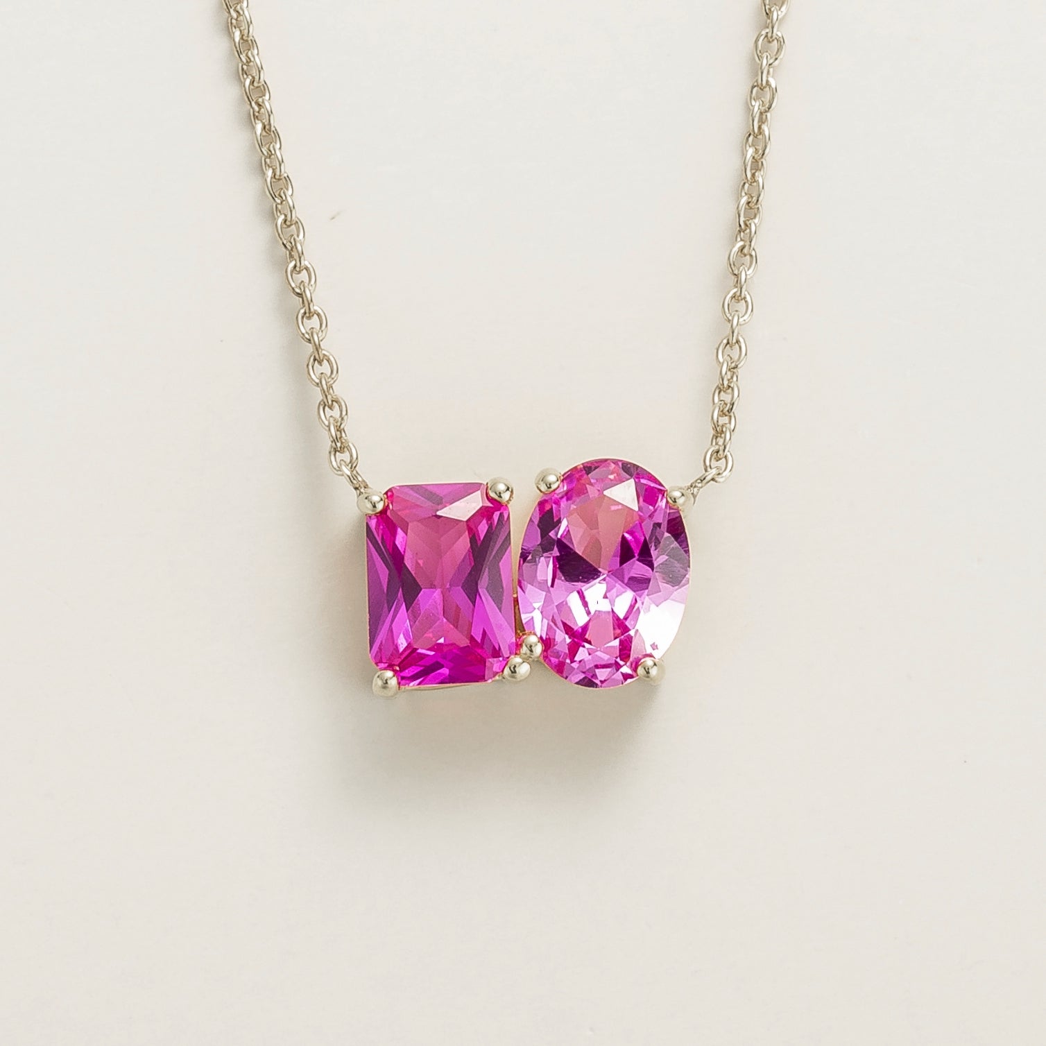 Toi et Moi white gold necklace featuring emerald vivid pink sapphire cut and oval cut pastel pink sapphires. London jewellery store
