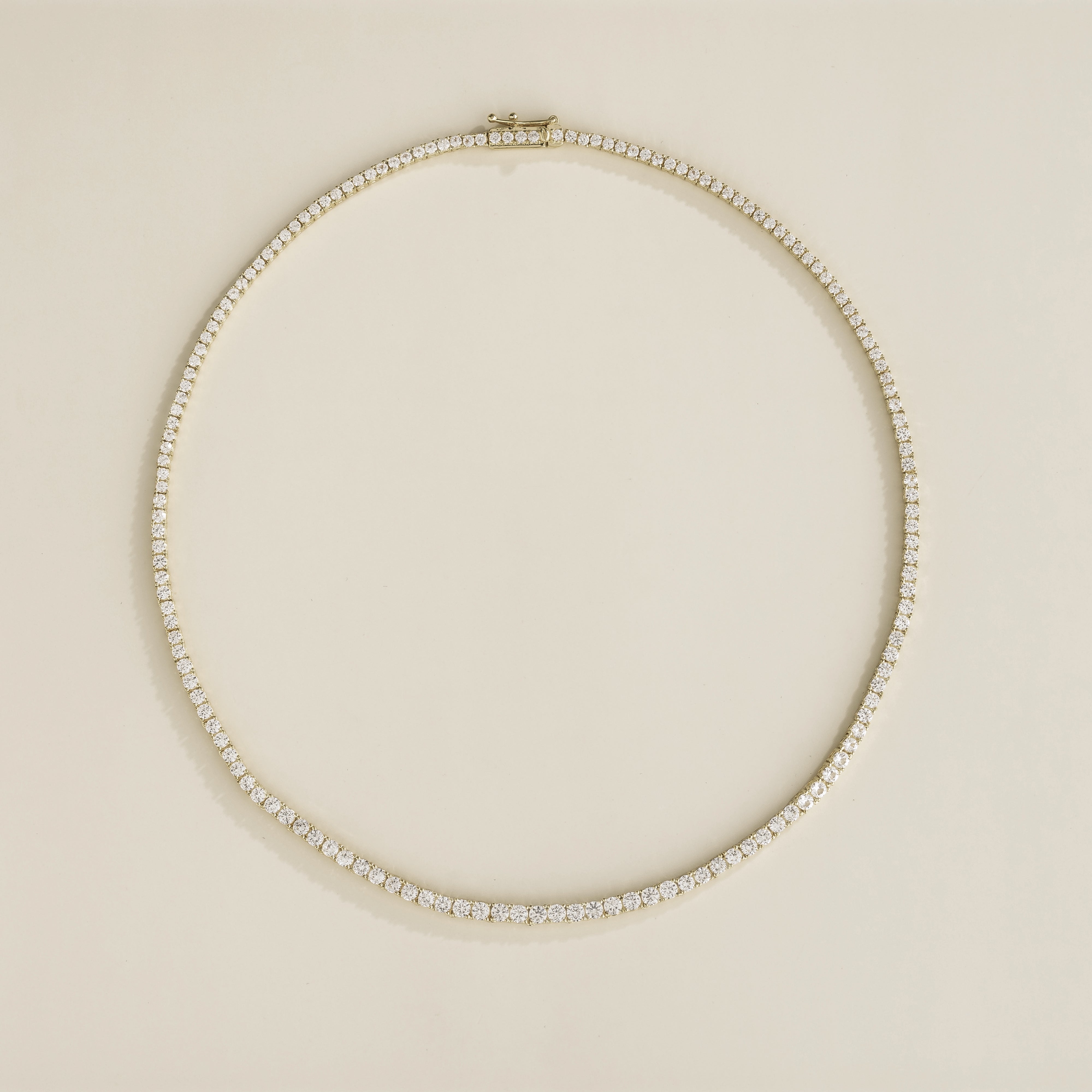 A white gold tennis necklace with a series of white sapphire stones set along its length.