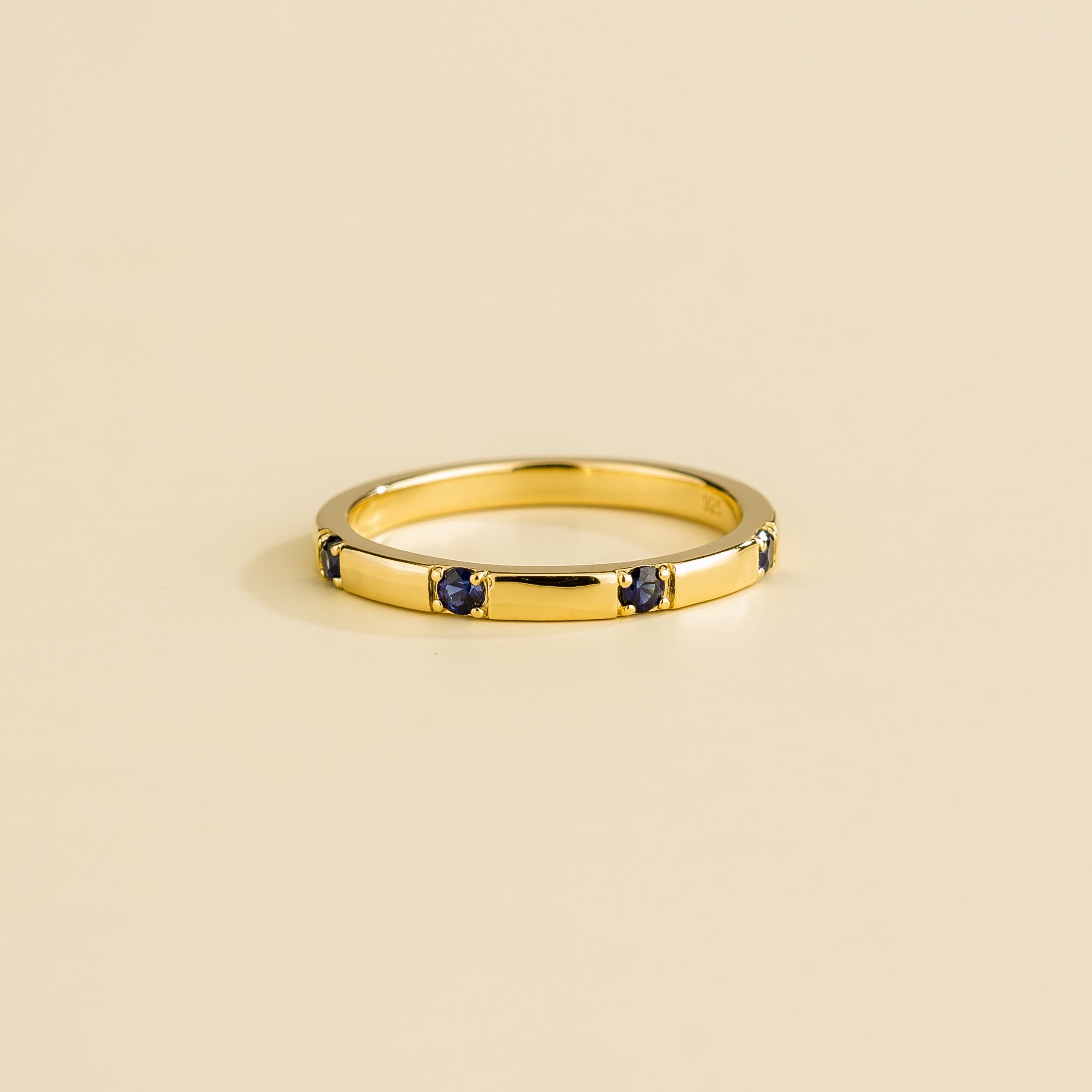 Juvetti yellow gold band set with round lab-grown royal blue sapphires in a sleek modern design.