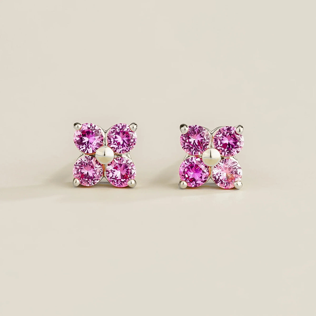 A pair of white gold stud earrings set with pink sapphires clover design, displayed against a plain background.