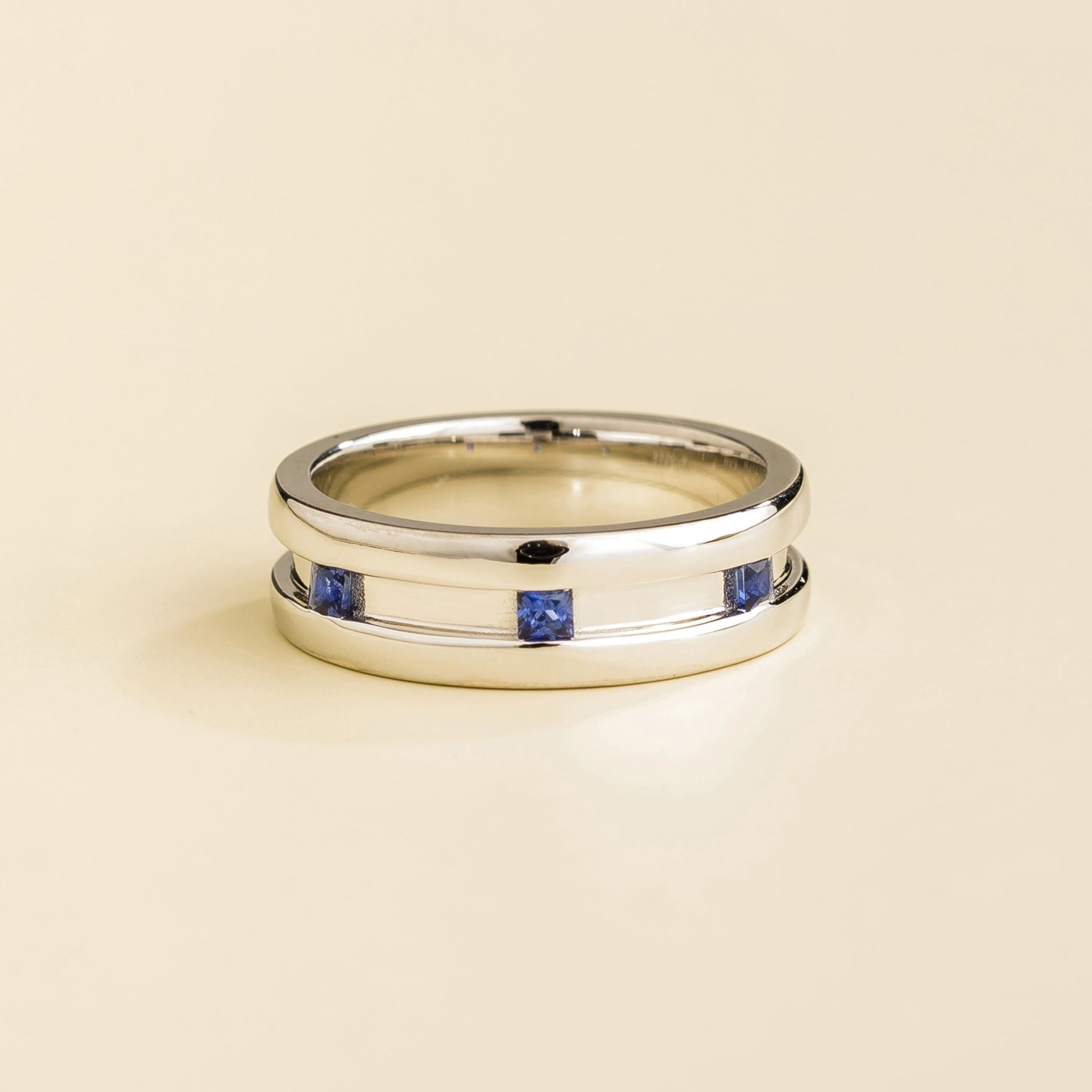 A white gold ring with blue sapphire gemstones set on a plain band.