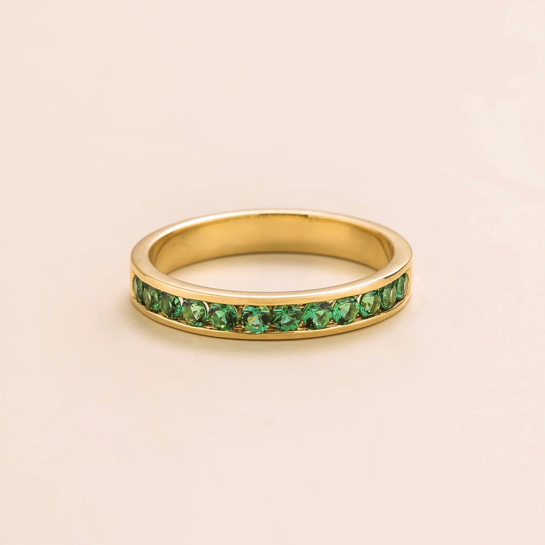 Juvetti yellow gold channel-set band featuring round lab-grown emerald gemstones.